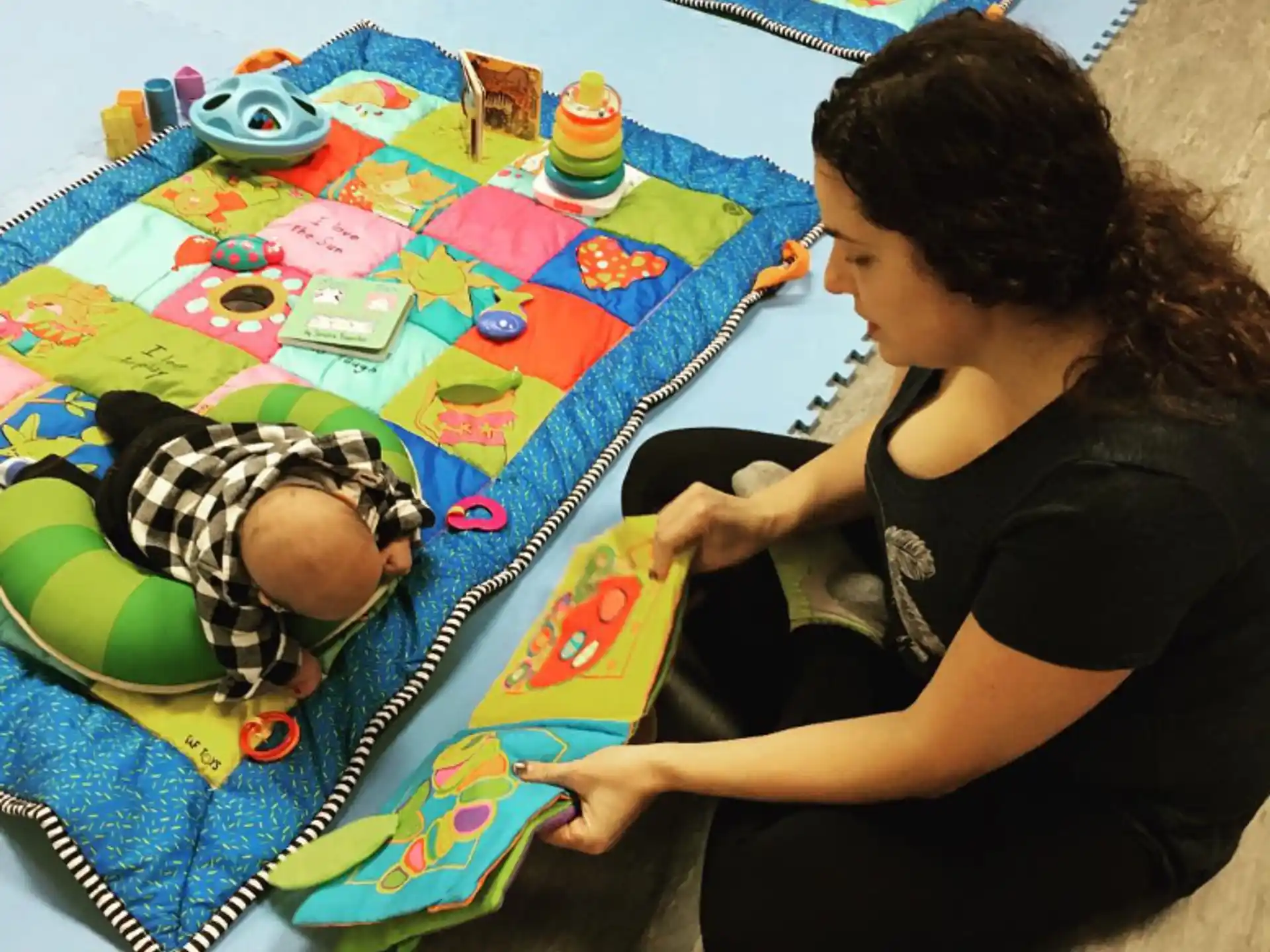 a woman and a baby playing on a colorful blanket