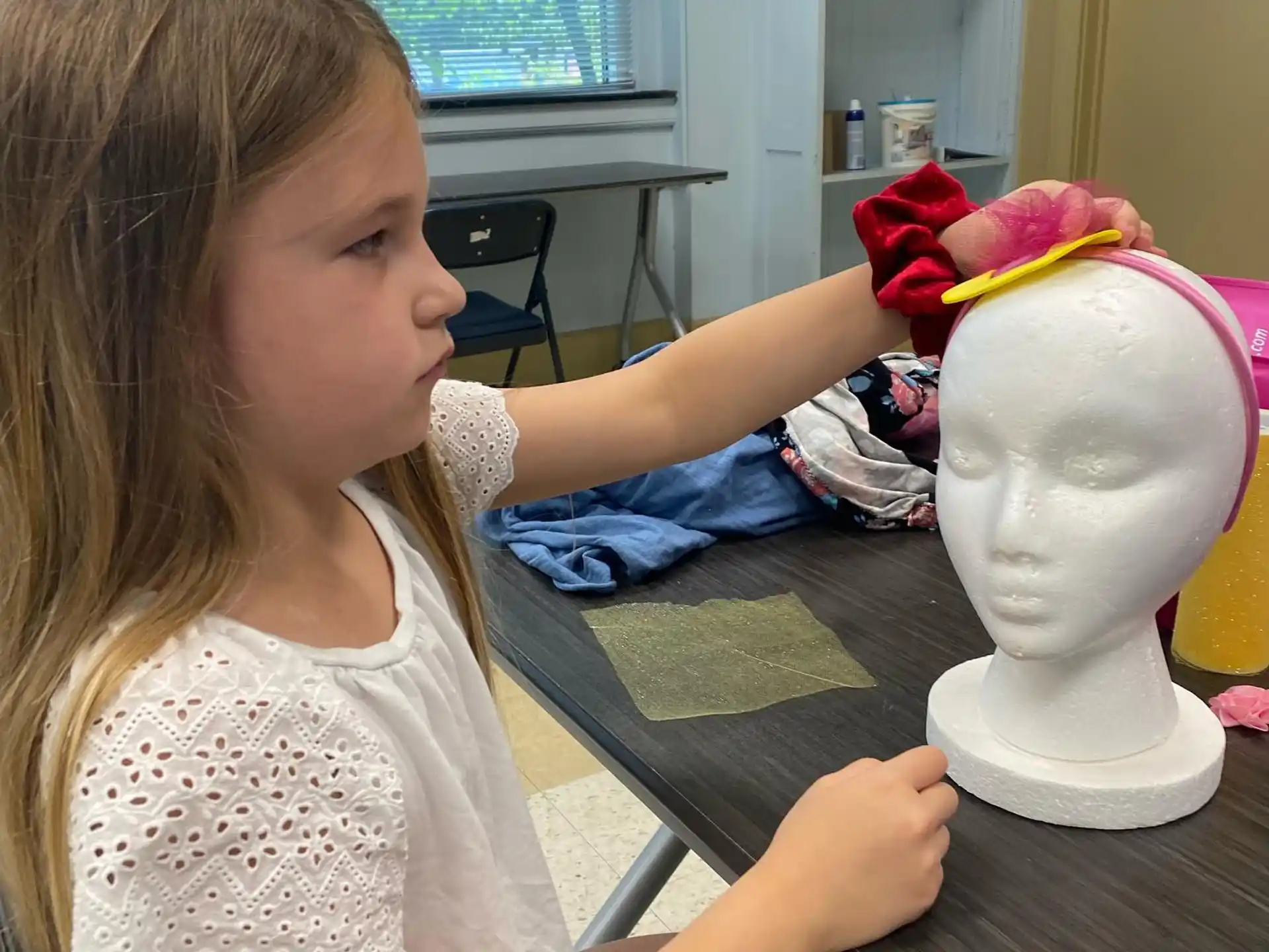 a girl sitting at a table with a toy