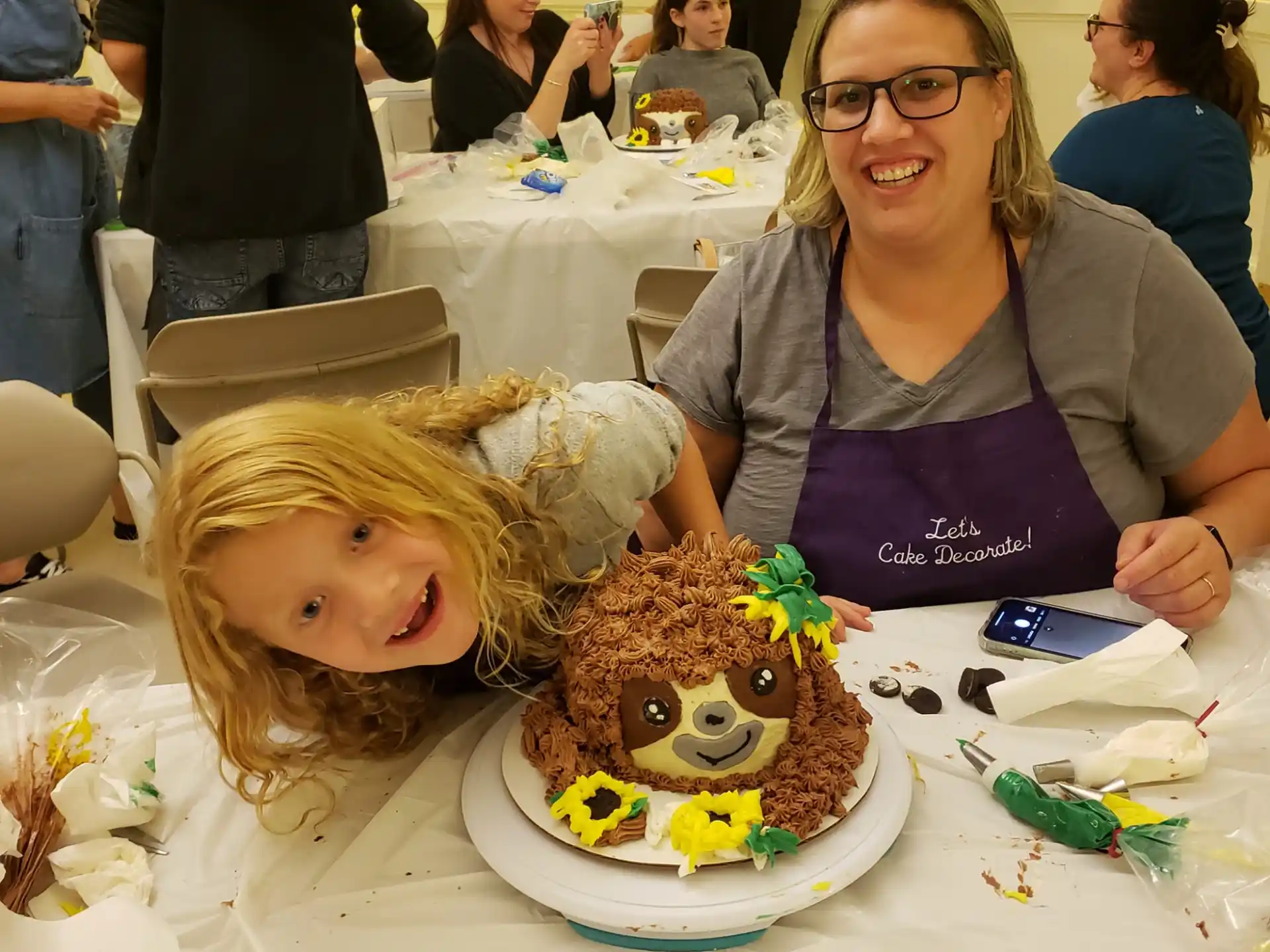 a woman and a girl sitting at a table with a cake