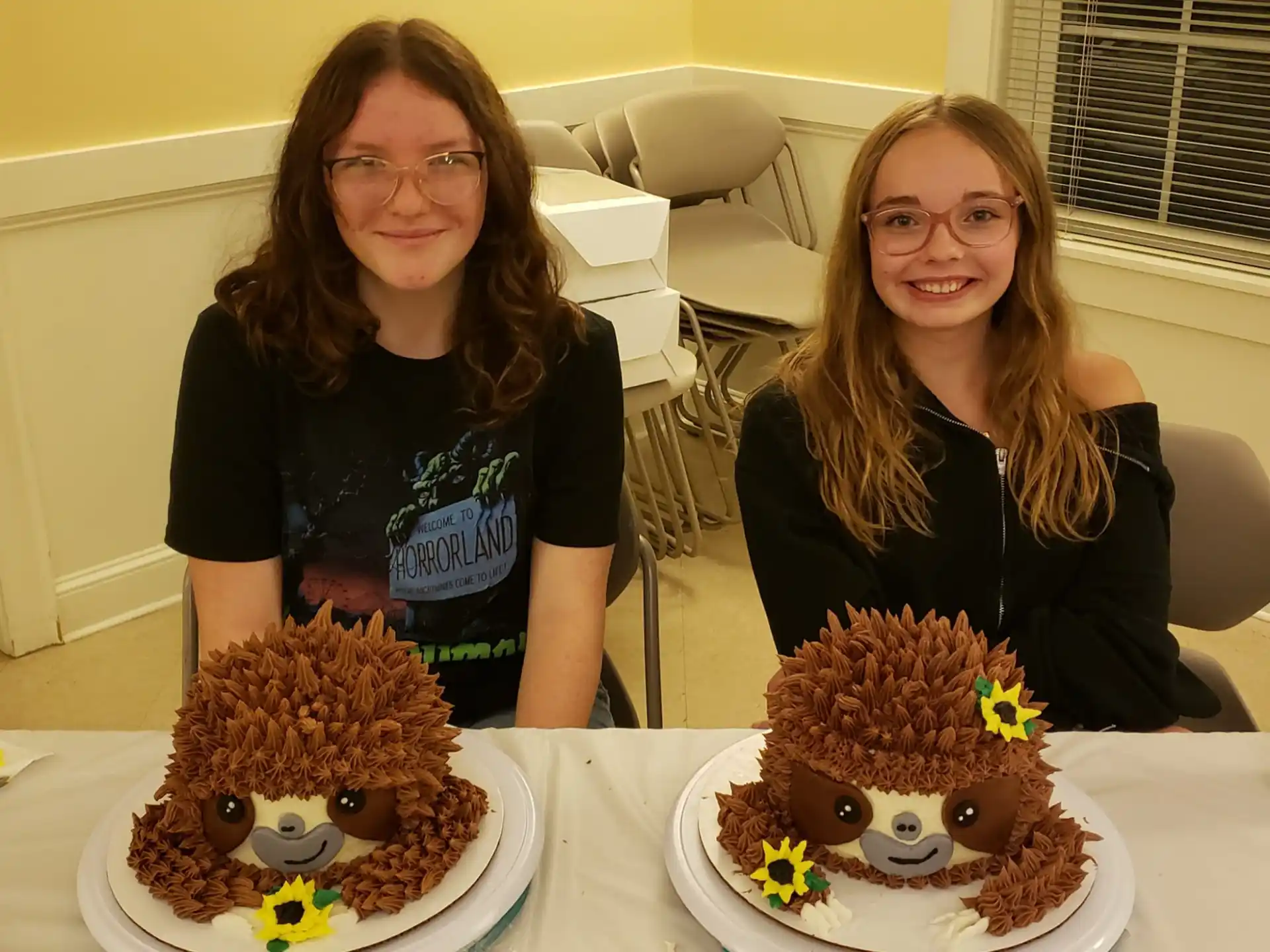 two women sitting at a table with a cake