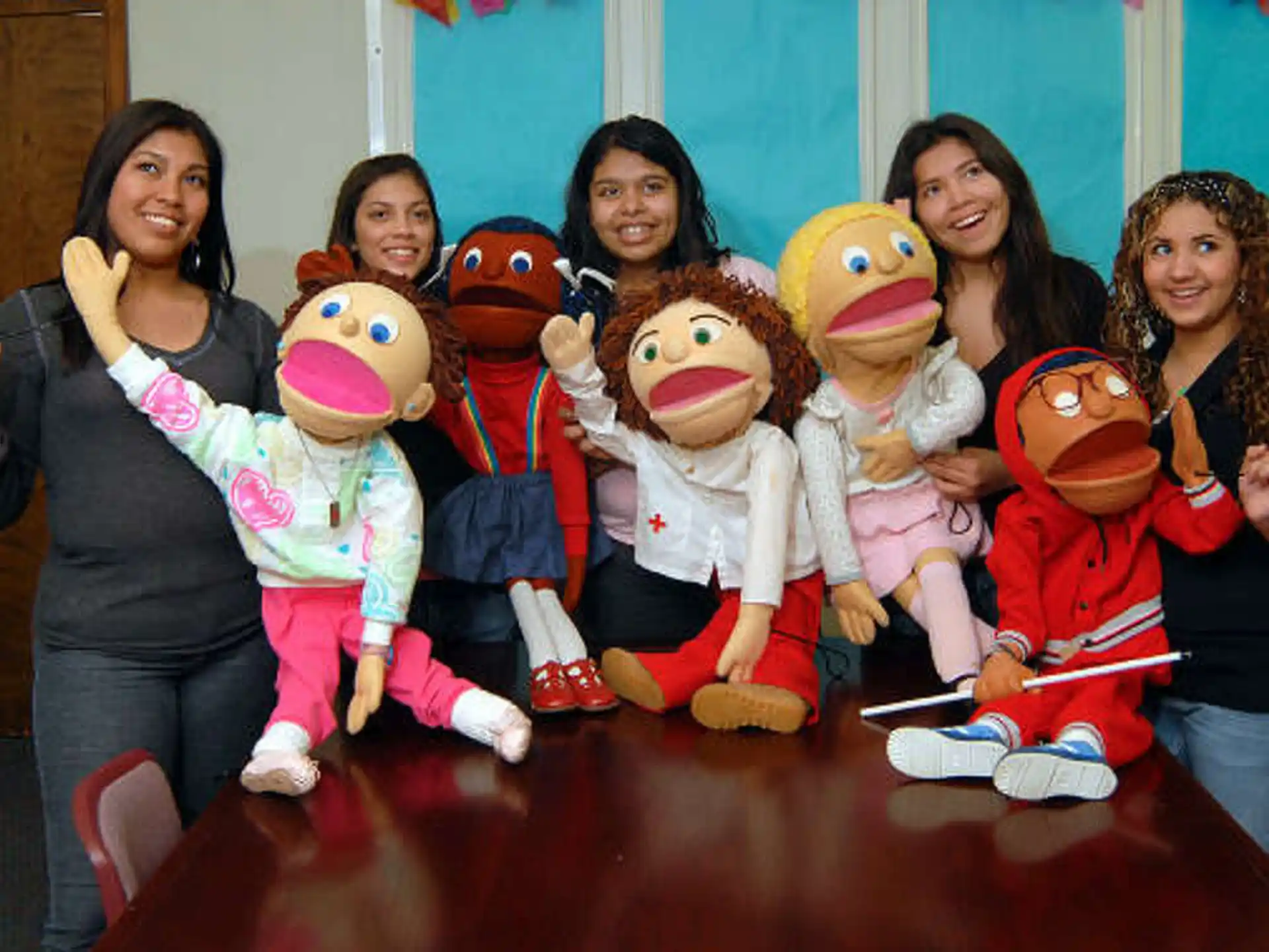 a group of women posing with a group of dolls