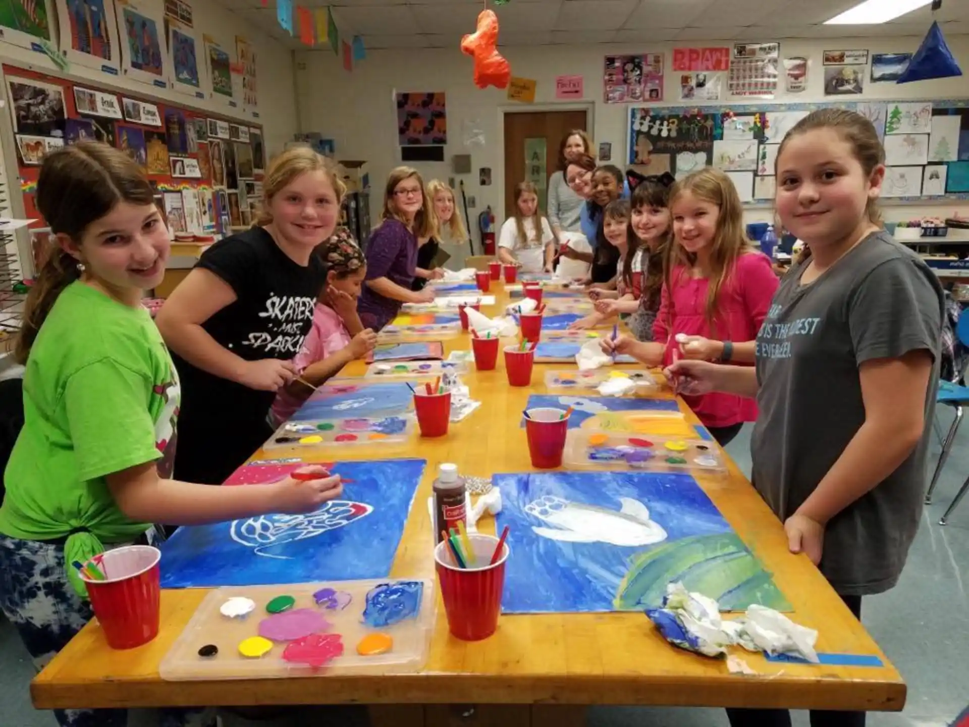 a group of children sitting at a table with cups and paper cups