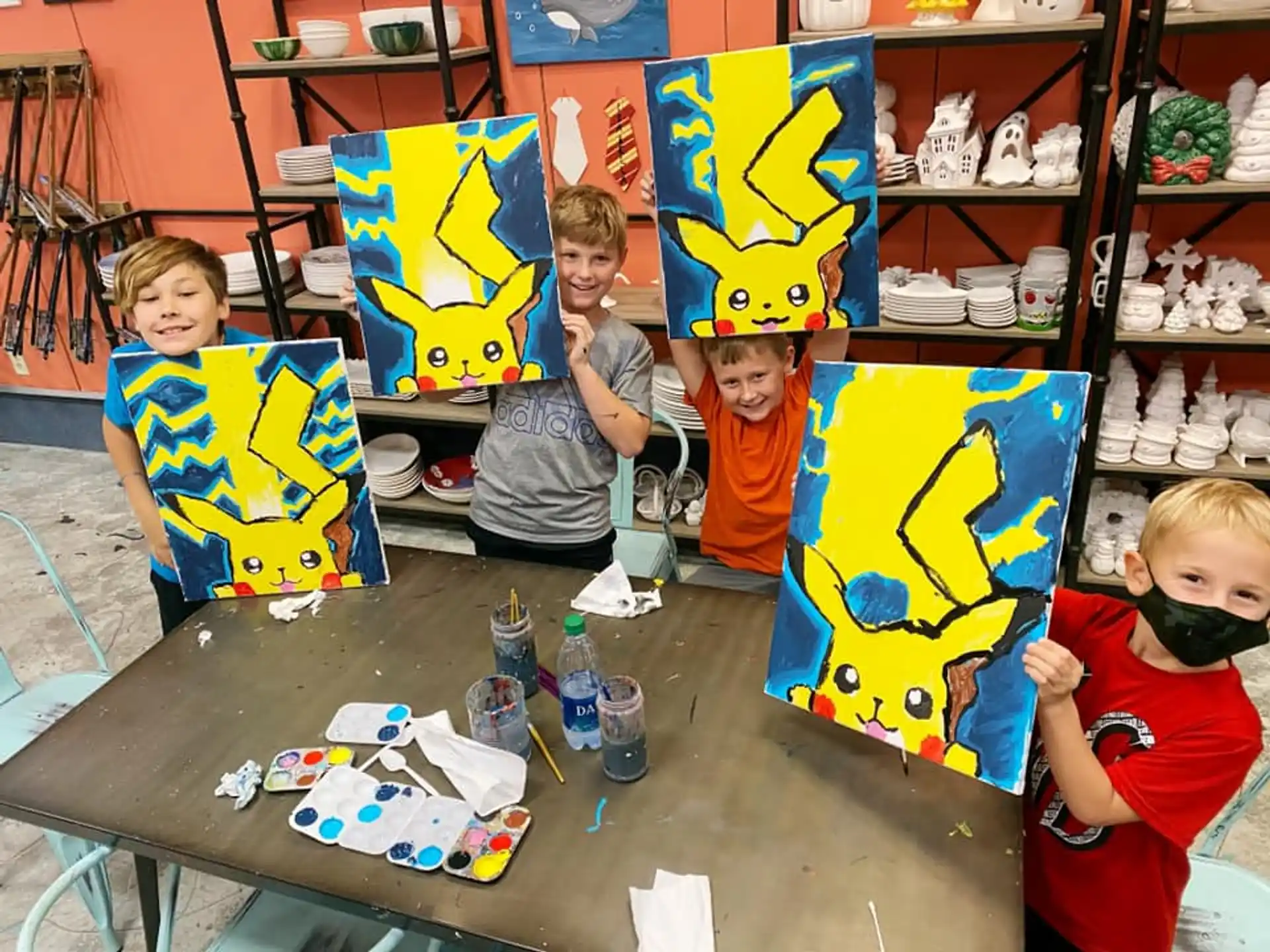 a group of kids sitting at a table with a large colorful kite