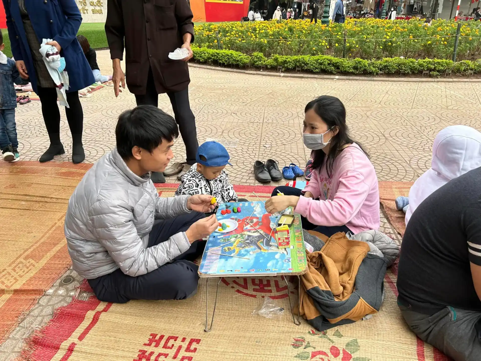 a group of people sitting on the ground with a table with a painting