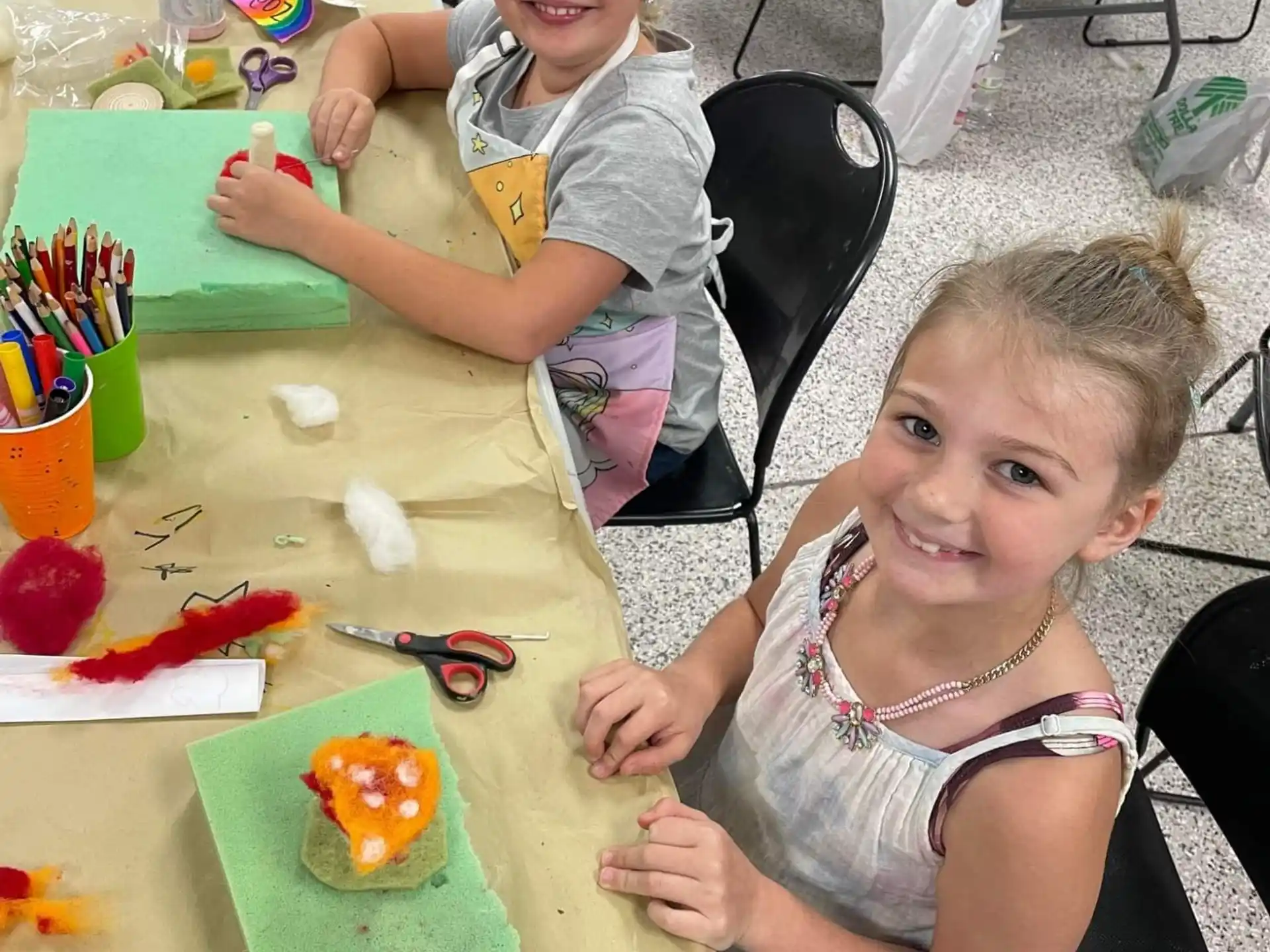 a person and a girl sitting at a table with art