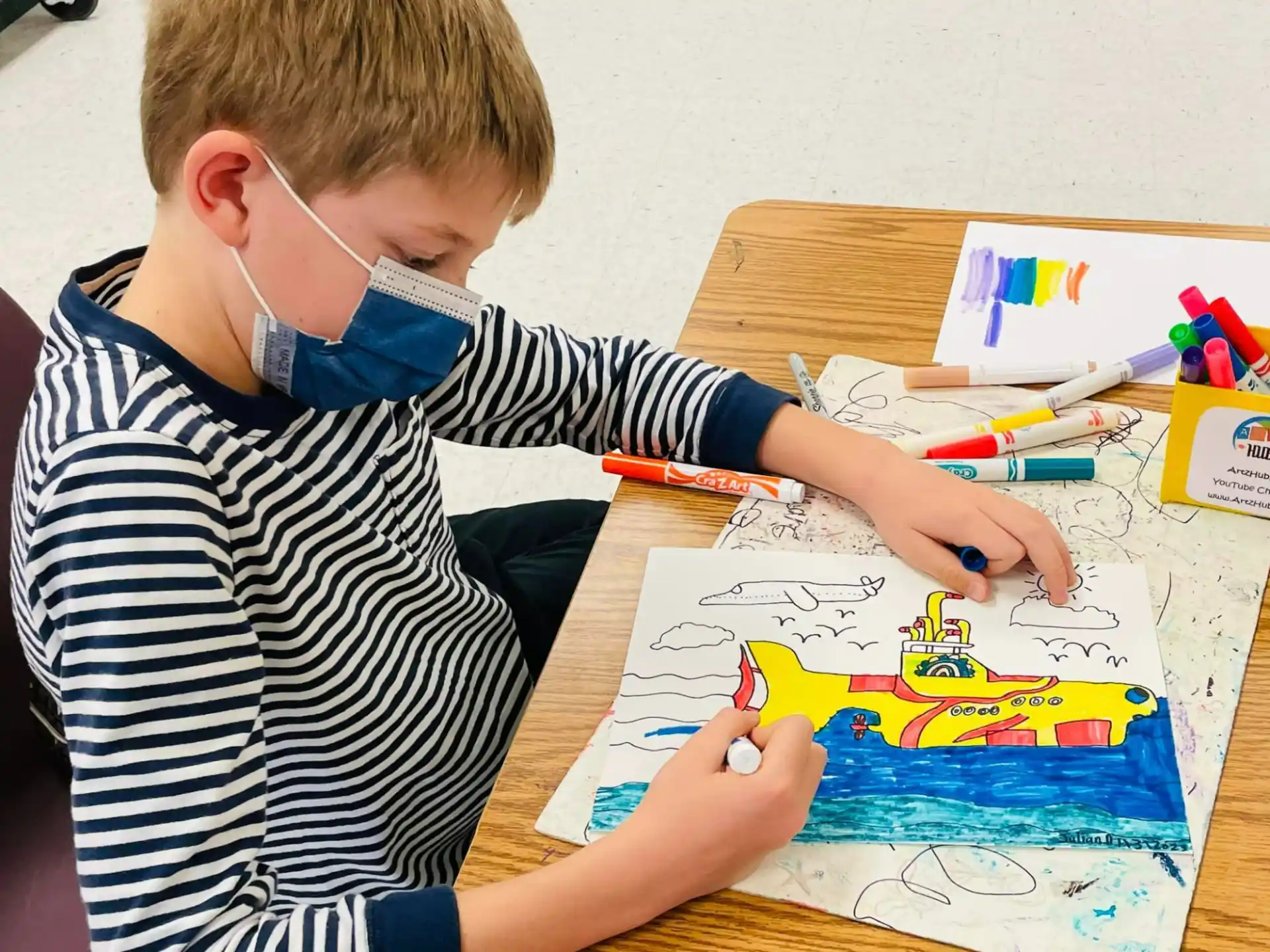 a boy sitting at a table with a toy