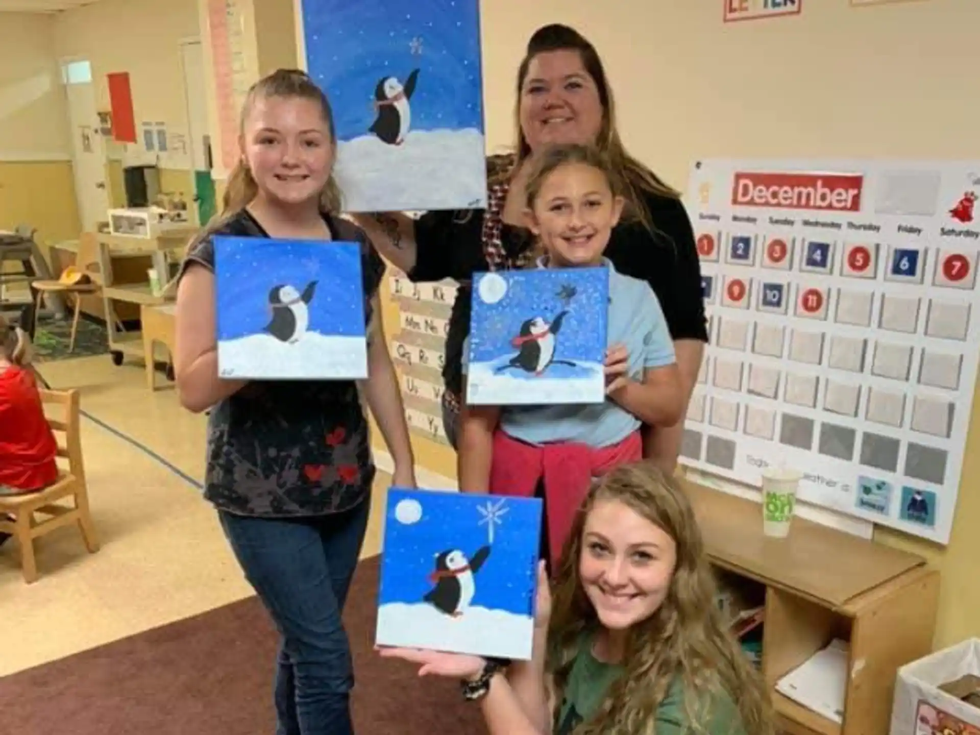 a group of girls holding up a blue and white box