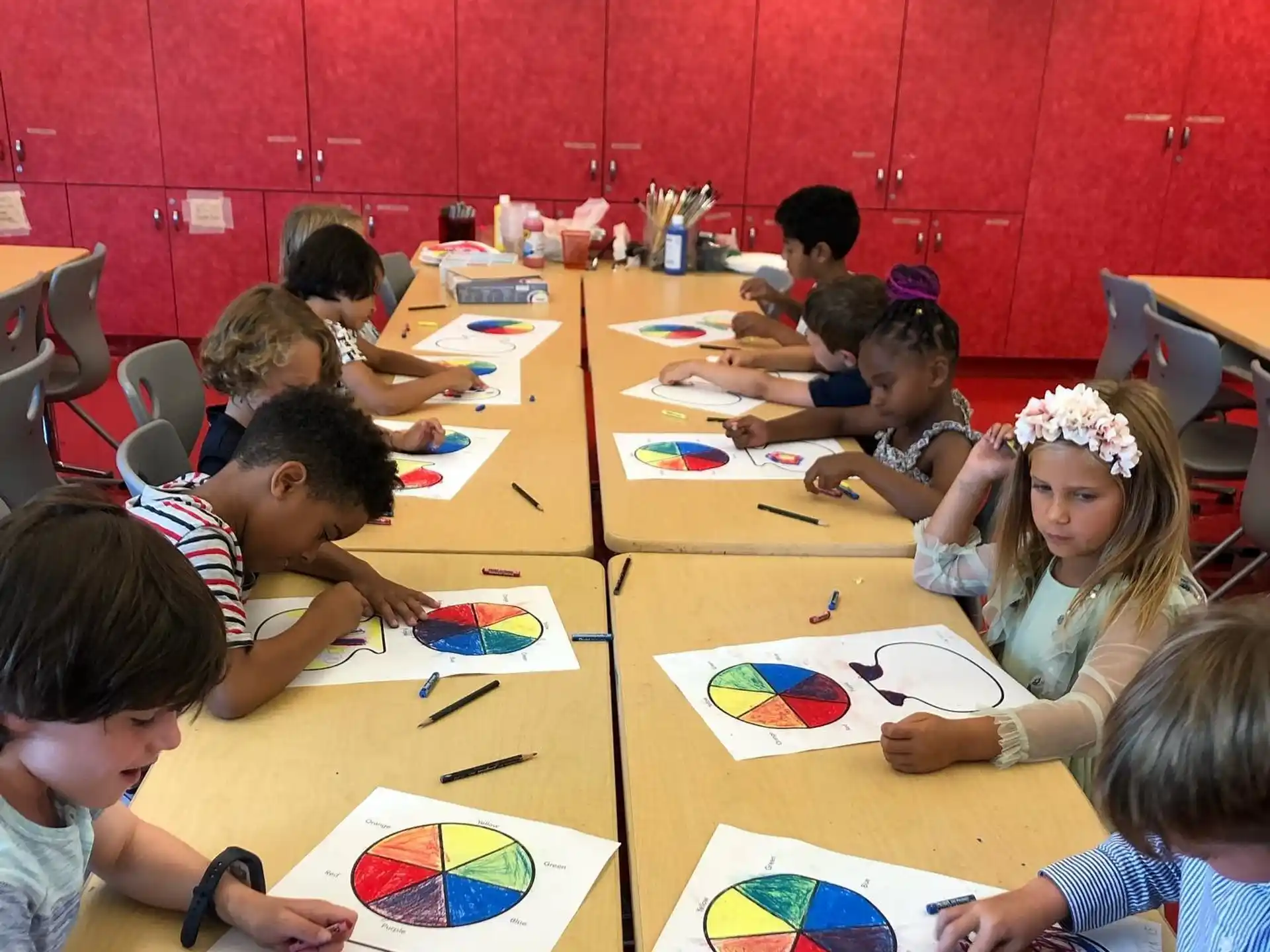 a group of children sitting at a table with colorful paper on it