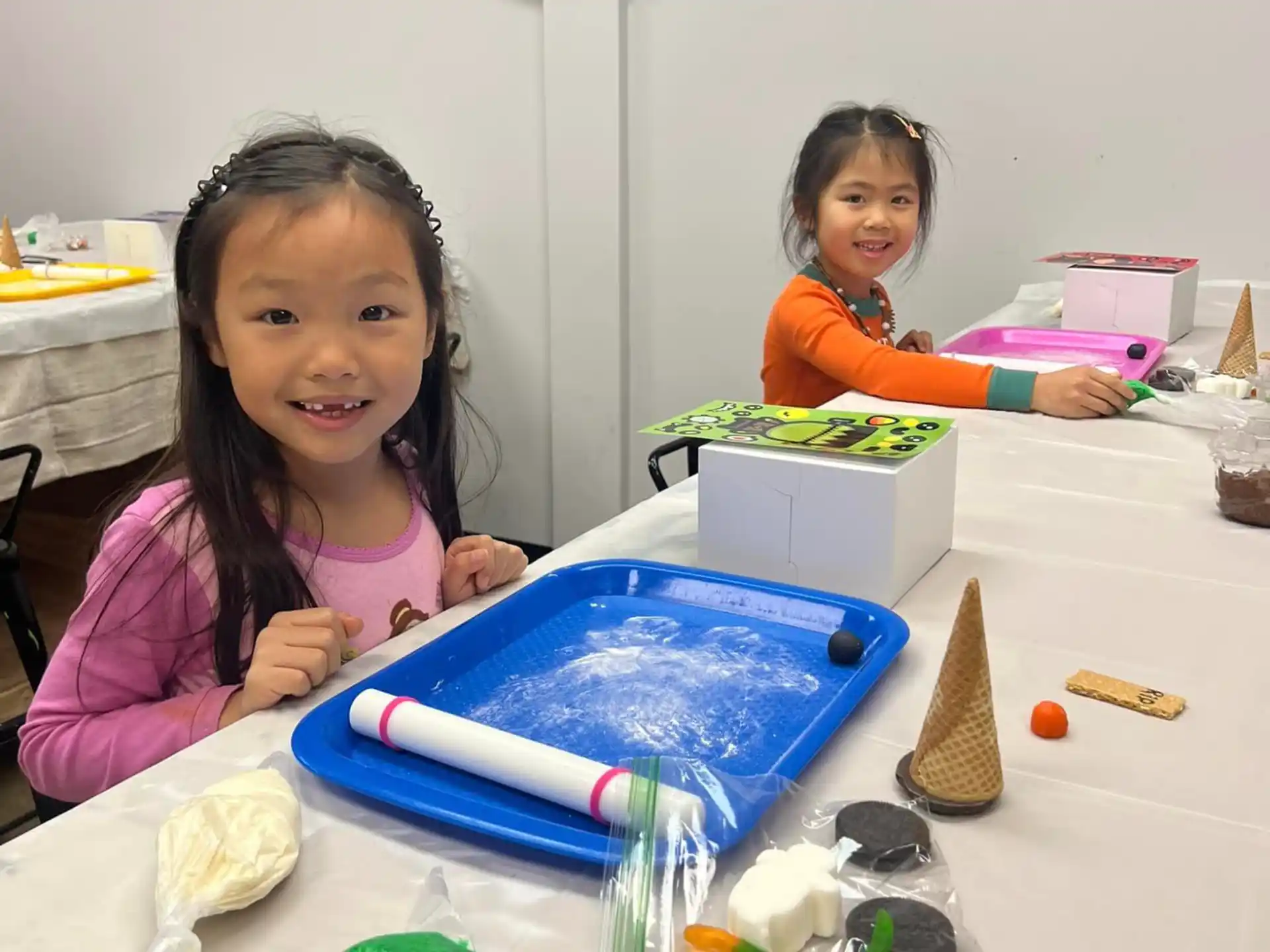 a couple of young girls sitting at a table with a blue pencil and a blue pencil