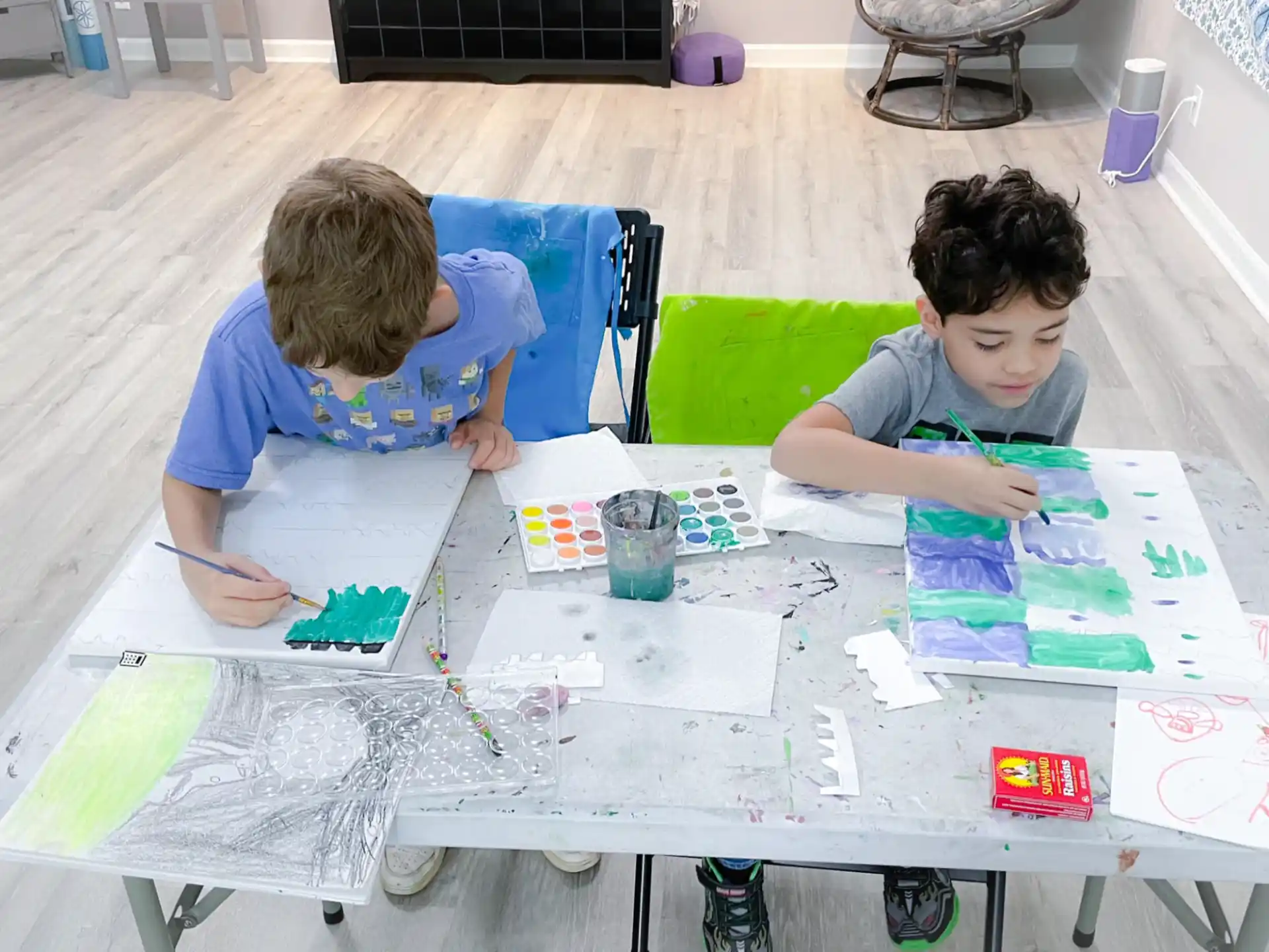a couple of boys sitting at a table with a drawing on it