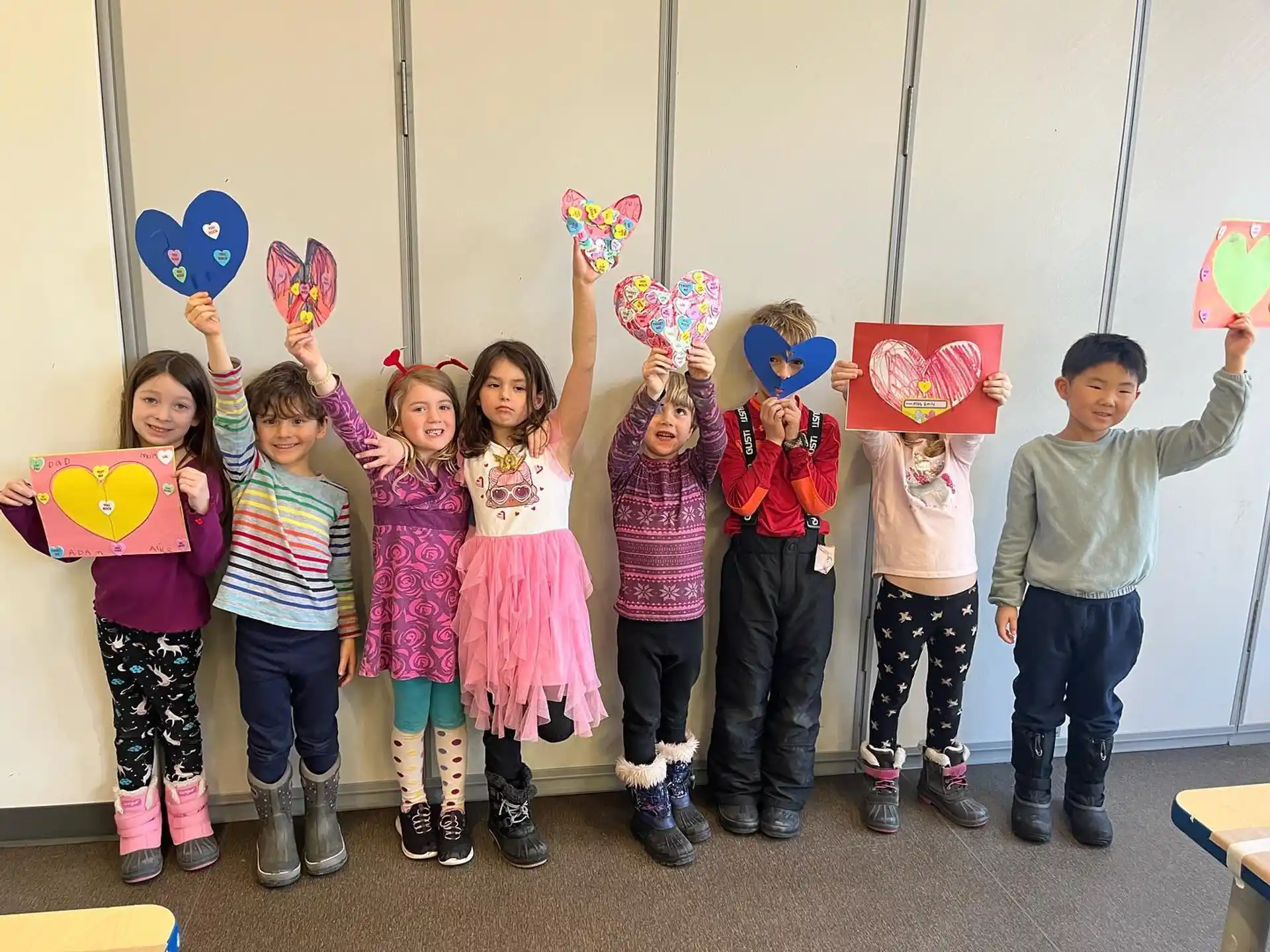 a group of children holding up colorful paper hearts