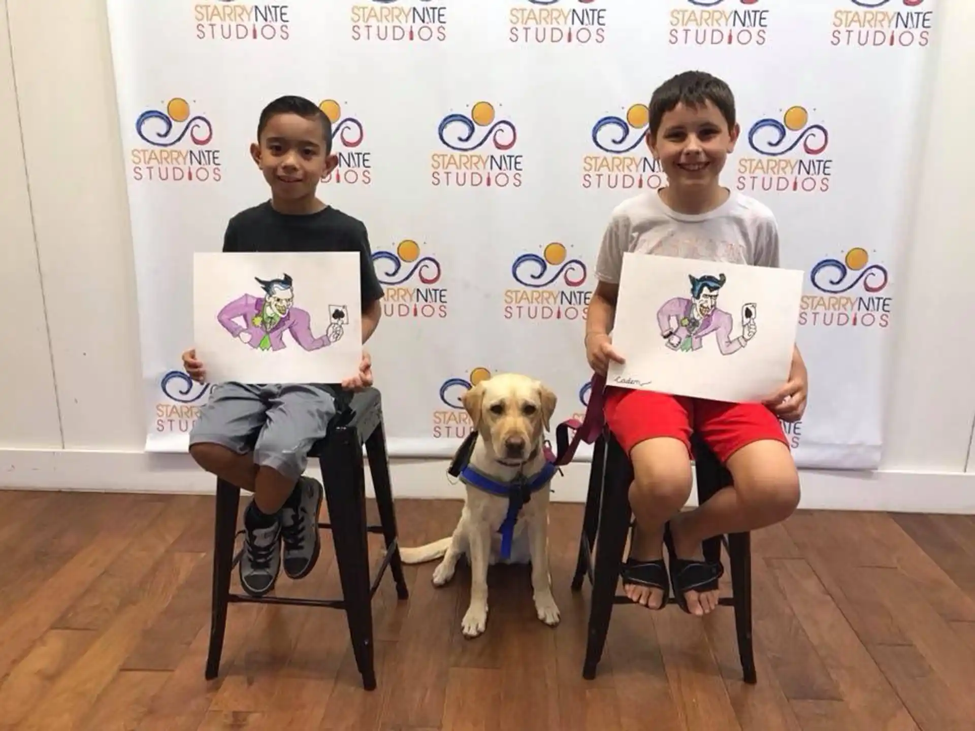 a couple of boys sitting in chairs with a dog and a sign