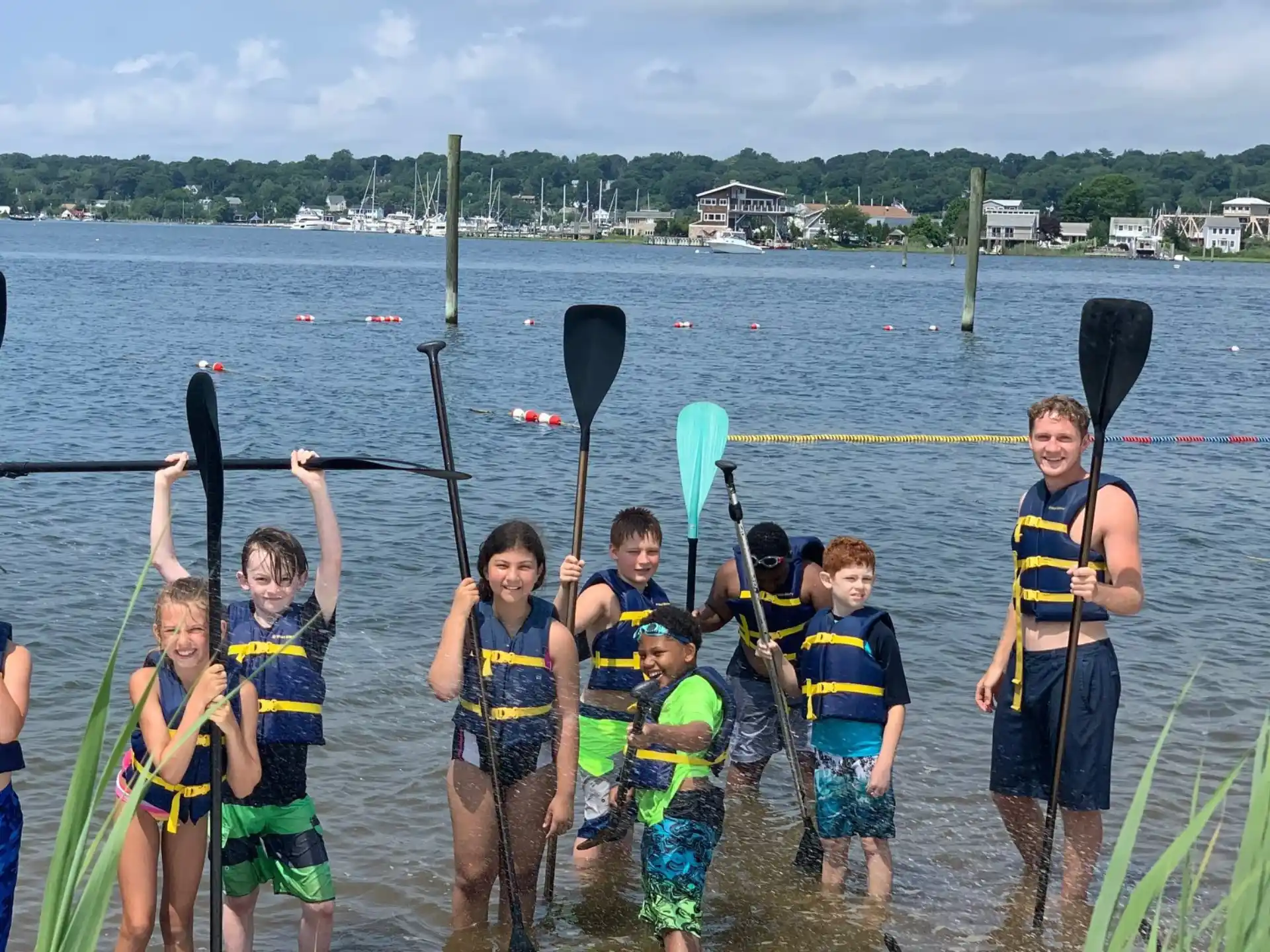 a group of people in life vests holding paddles in a lake