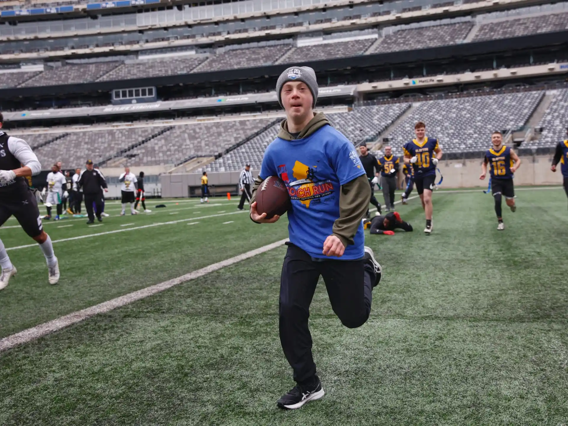 a person holding a football on a field with other people in the background