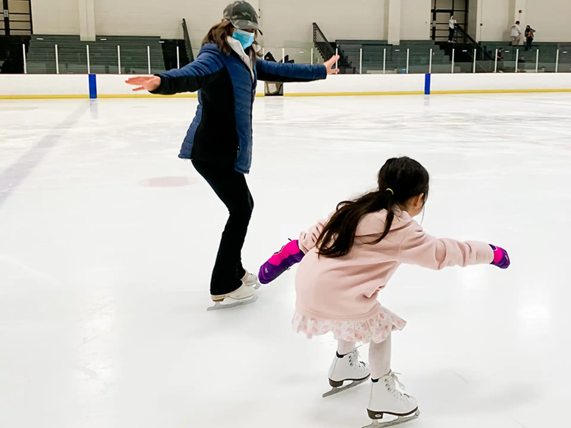 a person and a girl on an ice rink