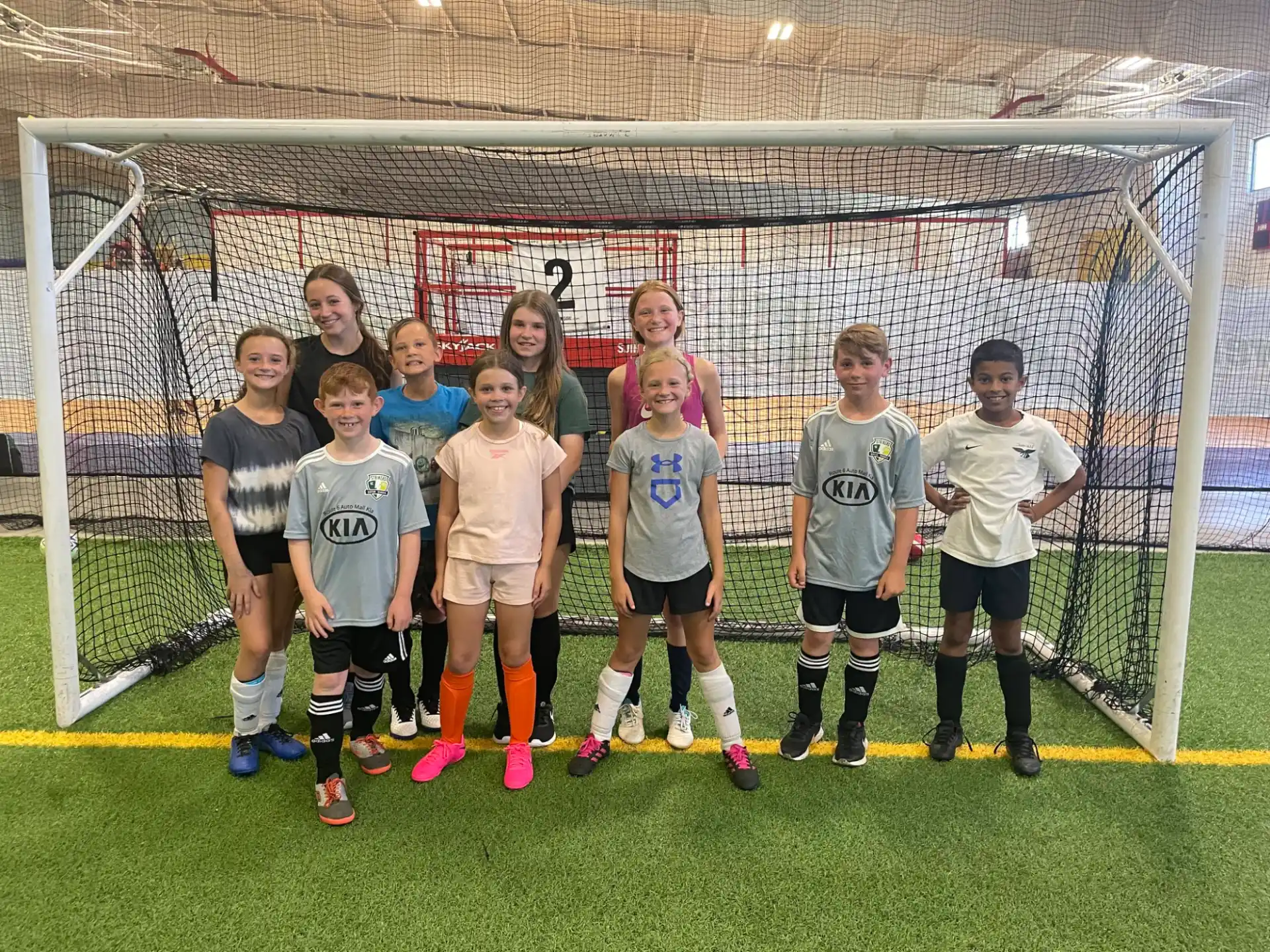 a group of kids posing for a picture in front of a football goal