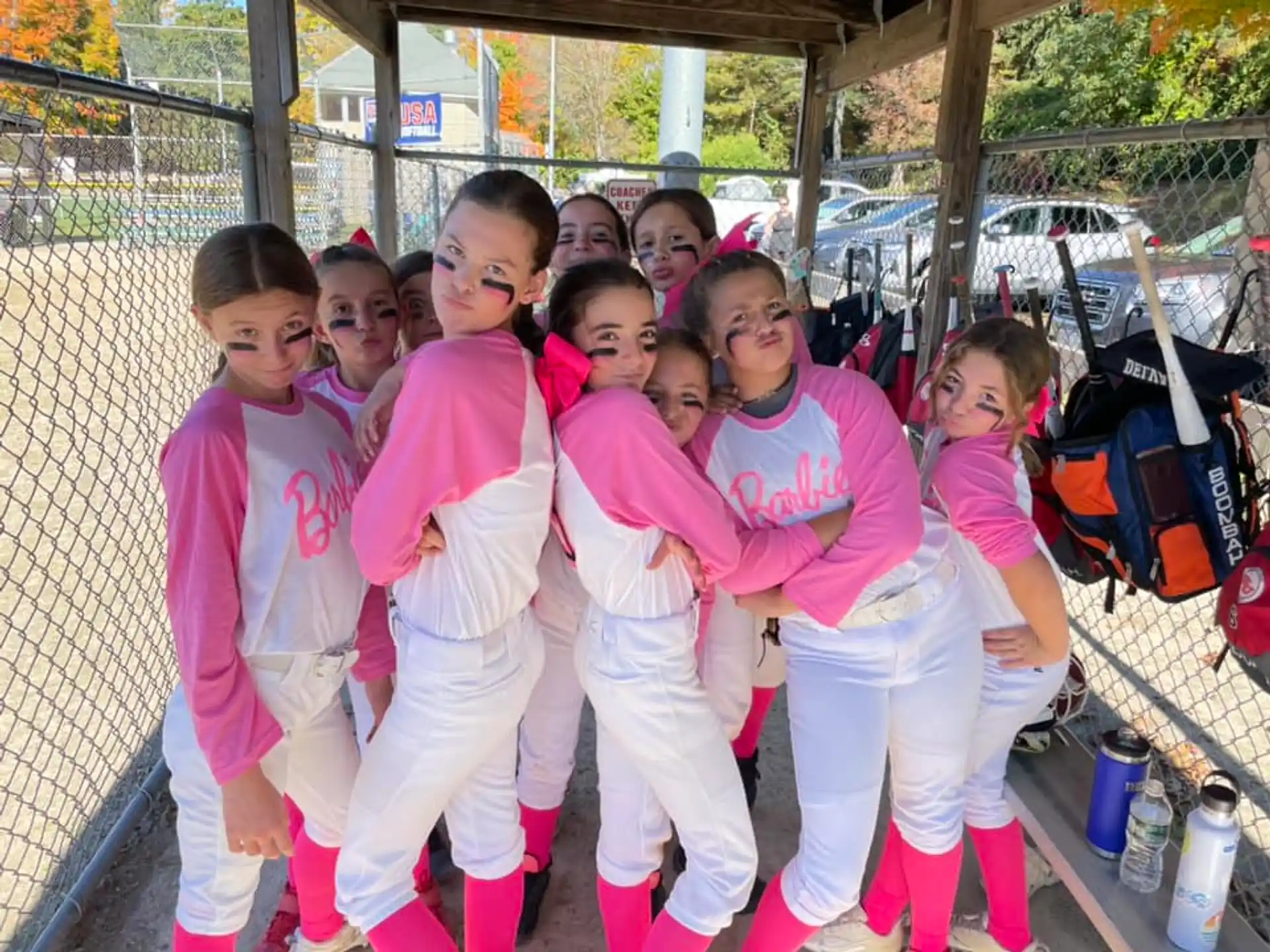 a group of girls in matching pink outfits standing in front of a fence