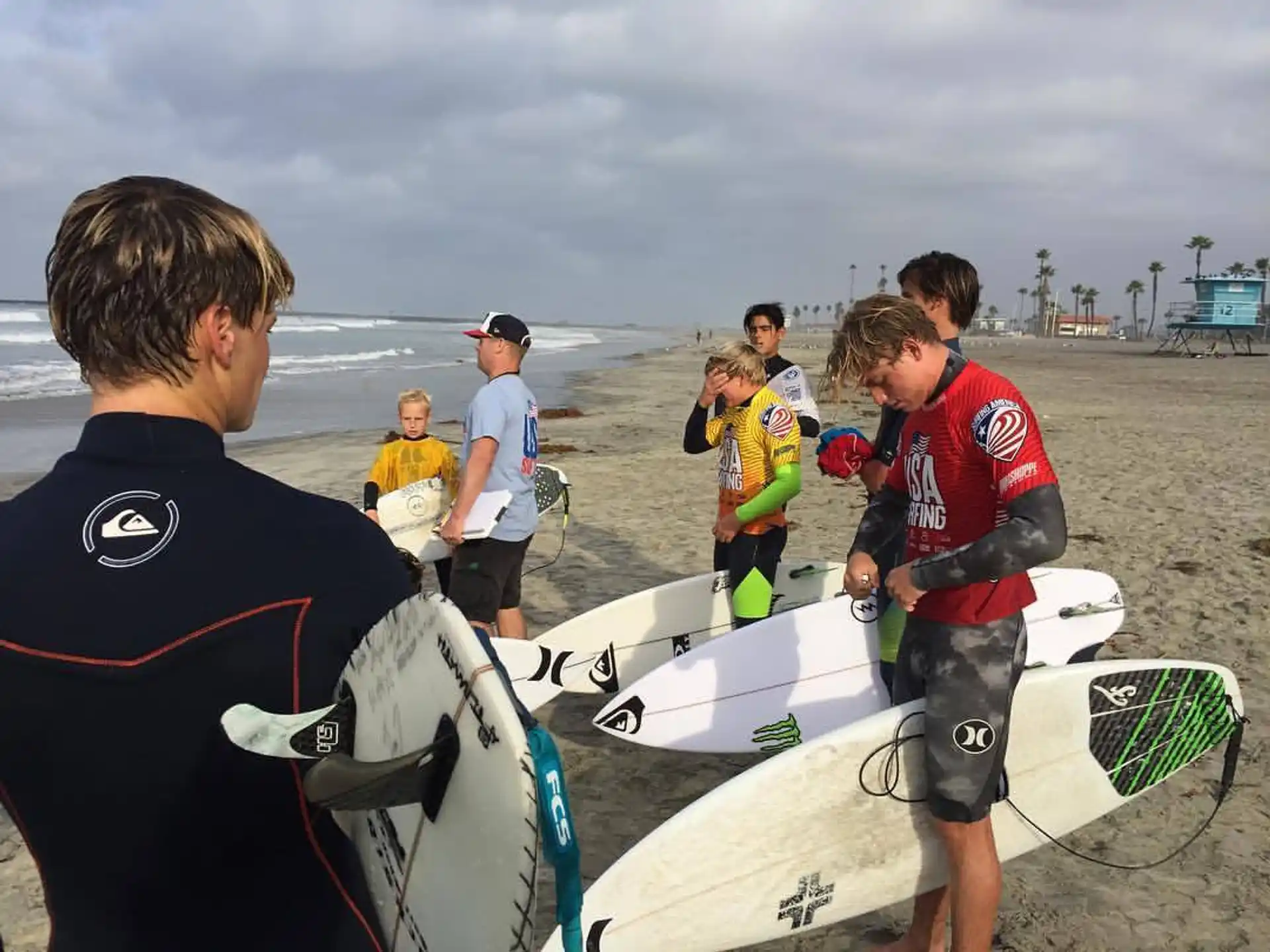 a group of surfers stand on the beach