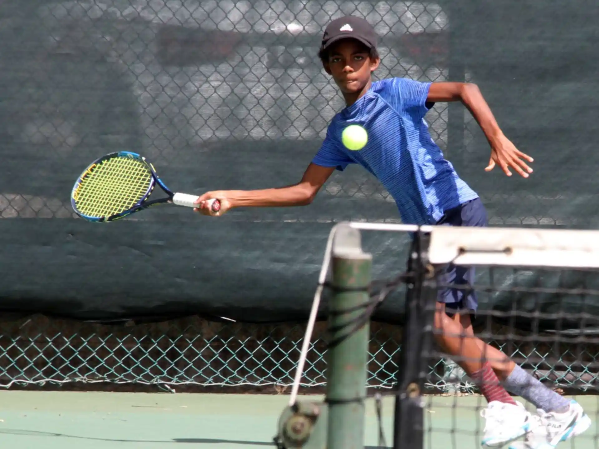 a boy hitting a ball with a tennis racket