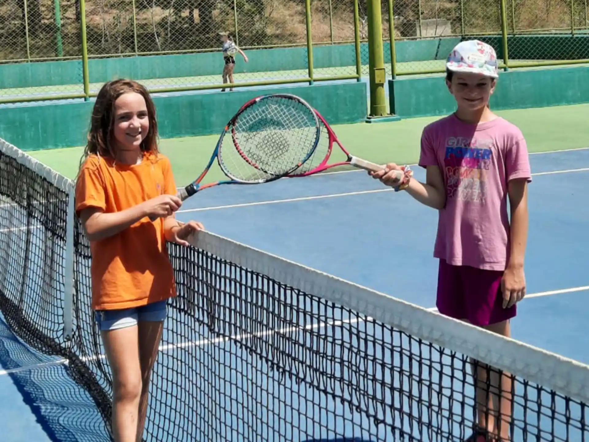 a couple of girls stand near each other holding tennis rackets