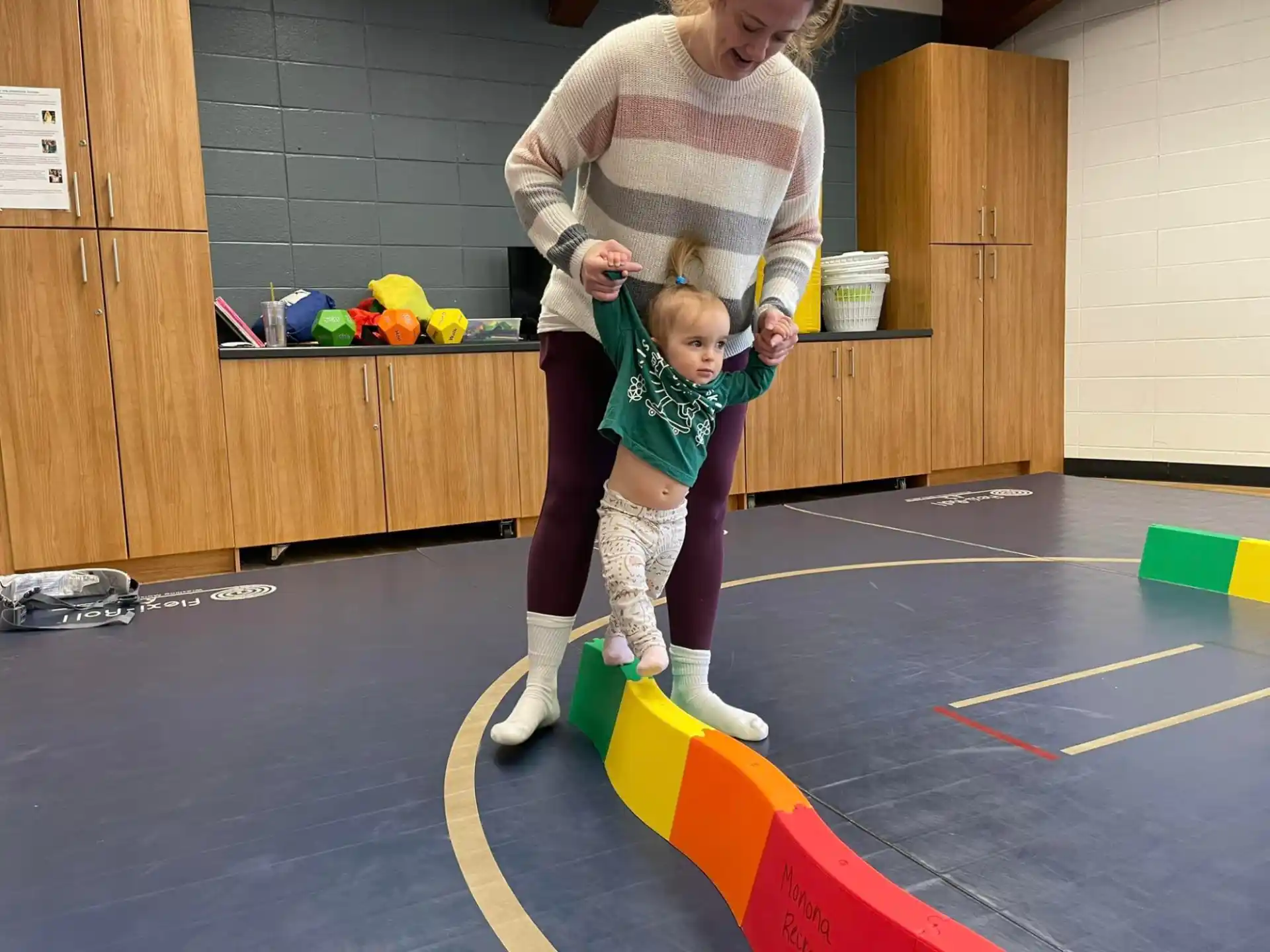 a person and a child playing on a mat in a gym