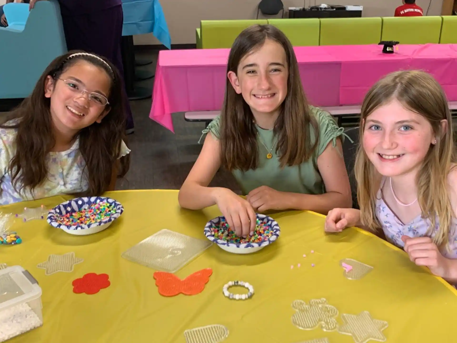 a group of girls sitting at a table with a cake