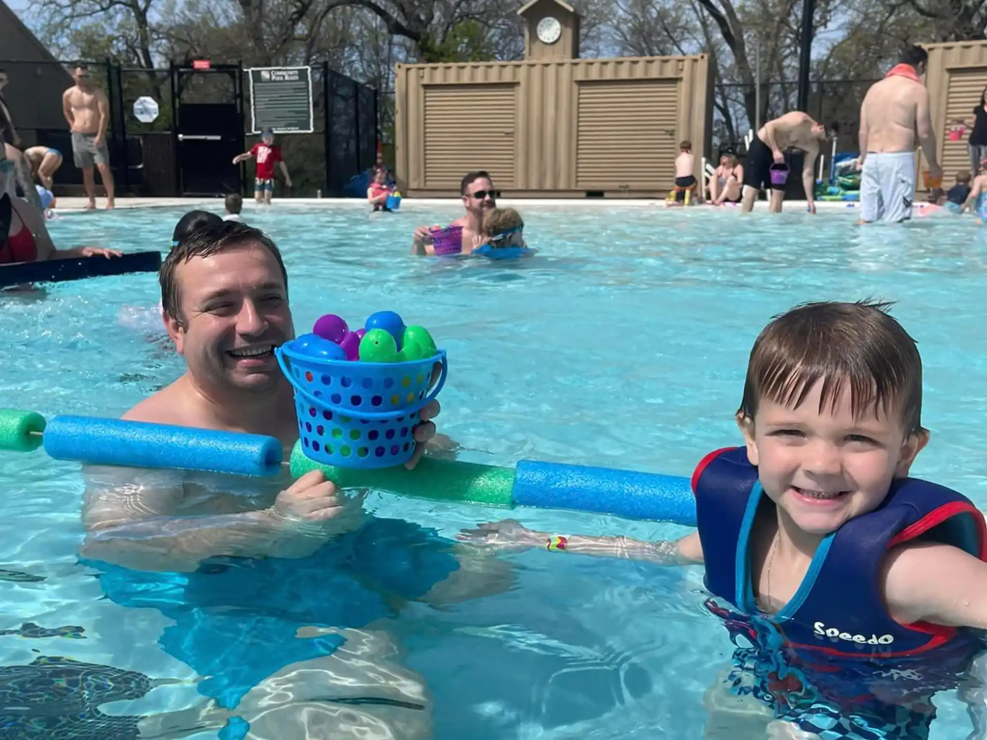 a person and a boy in a pool with a bucket of water