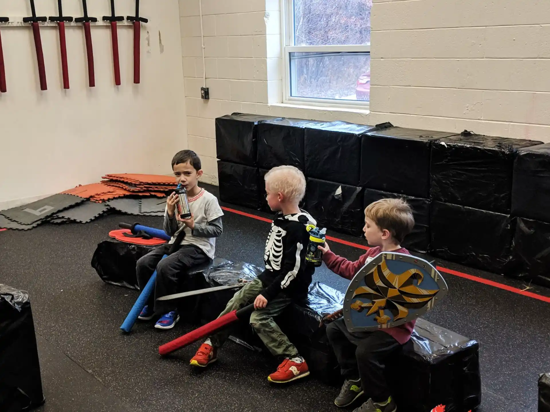 a group of boys sitting on the floor with a black object in front of them