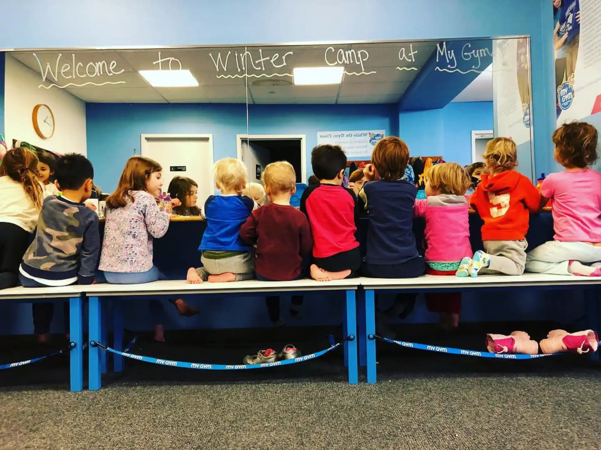 a group of children sitting on a blue bench
