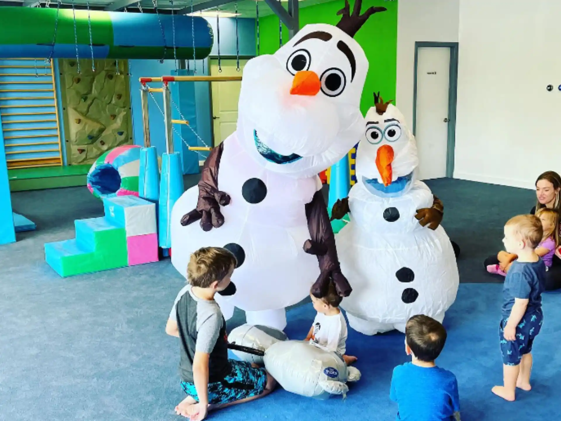 children sitting in front of a large white and blue cartoon character