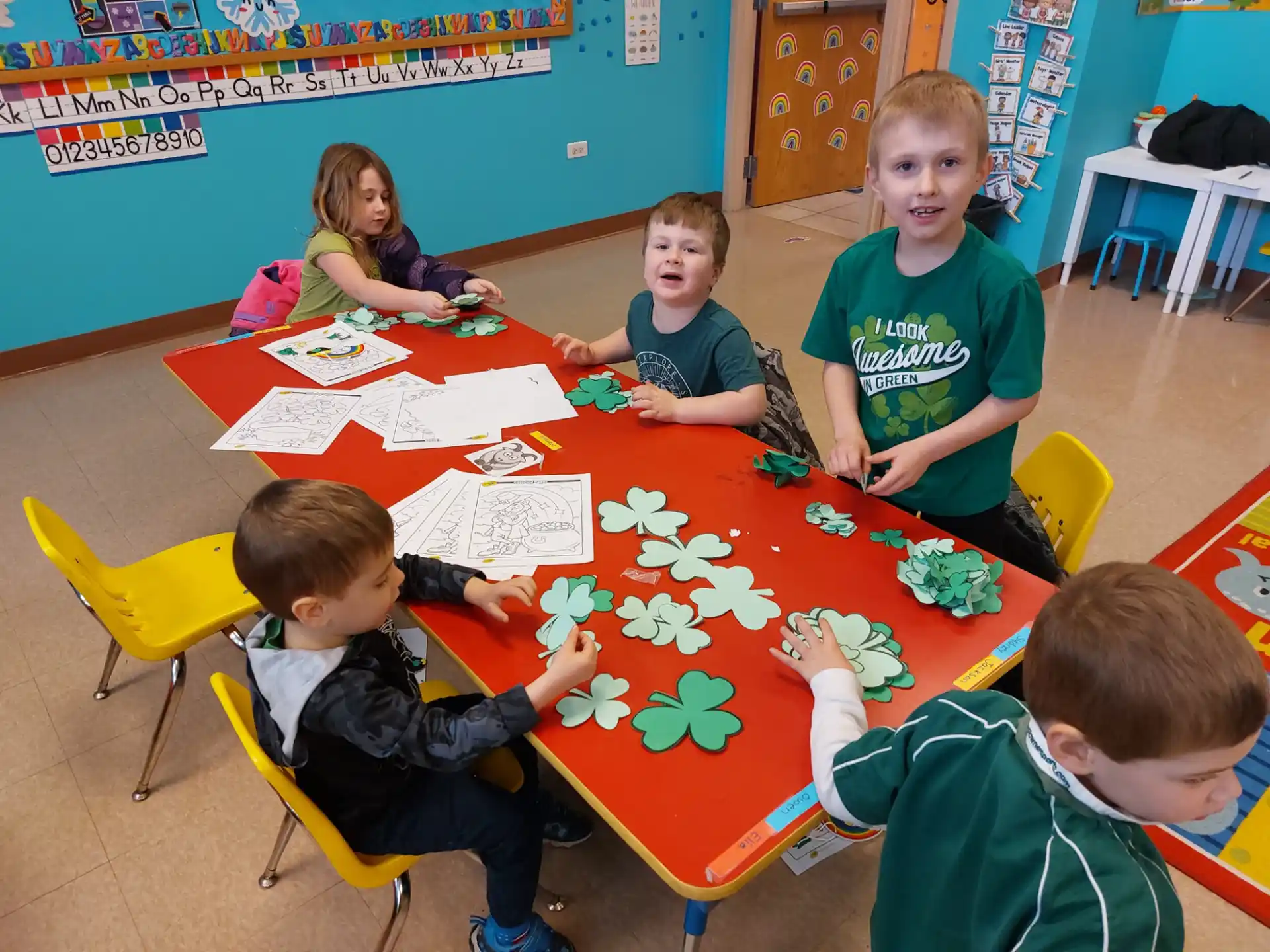 a group of children sitting around a table with a colorful tablecloth