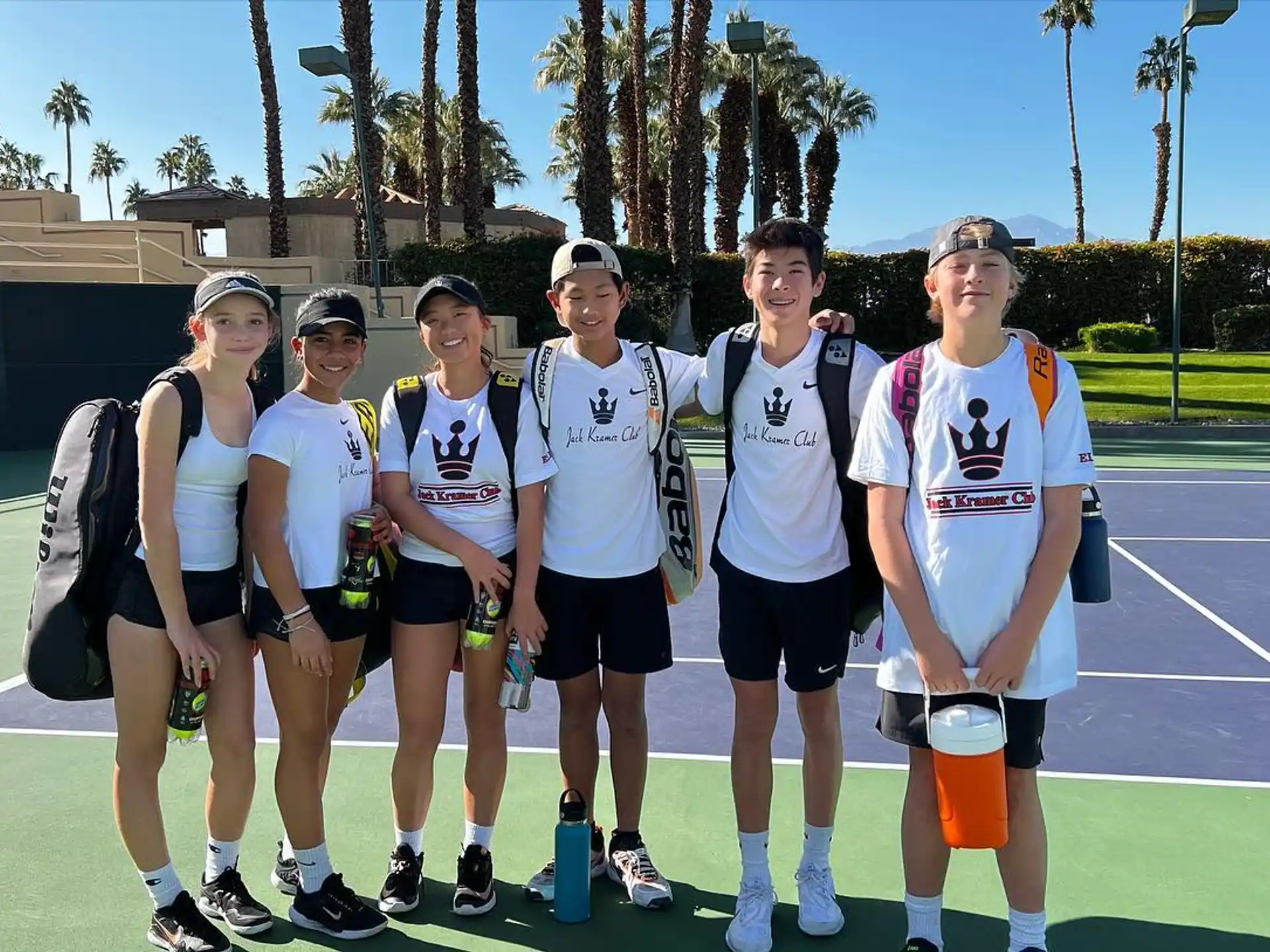 a group of people posing for a photo on a tennis court