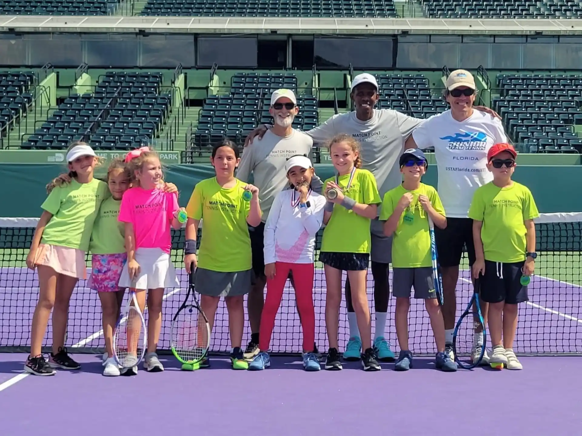 a group of people pose for a photo on a tennis court