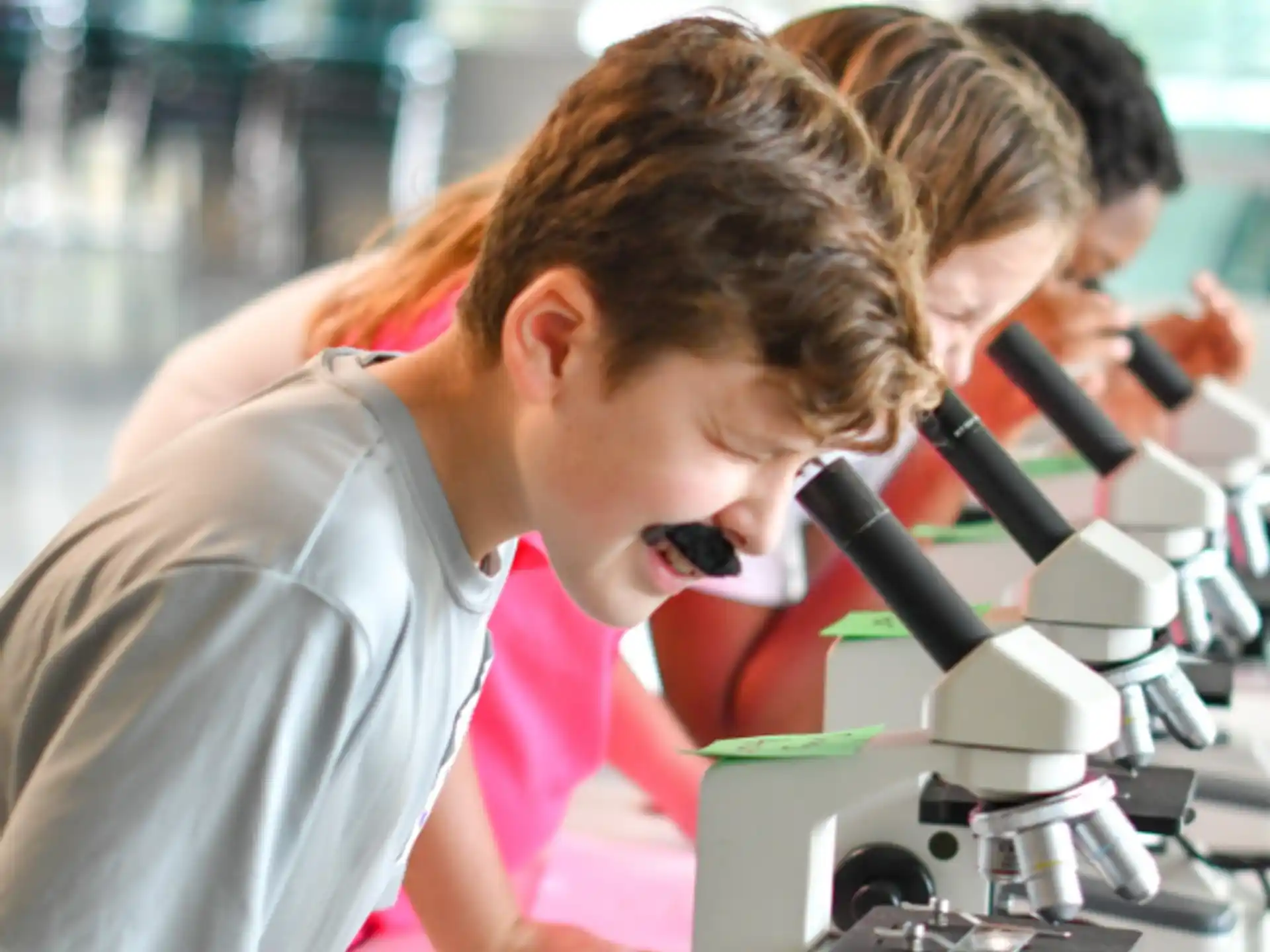 a young girl looking through a microscope