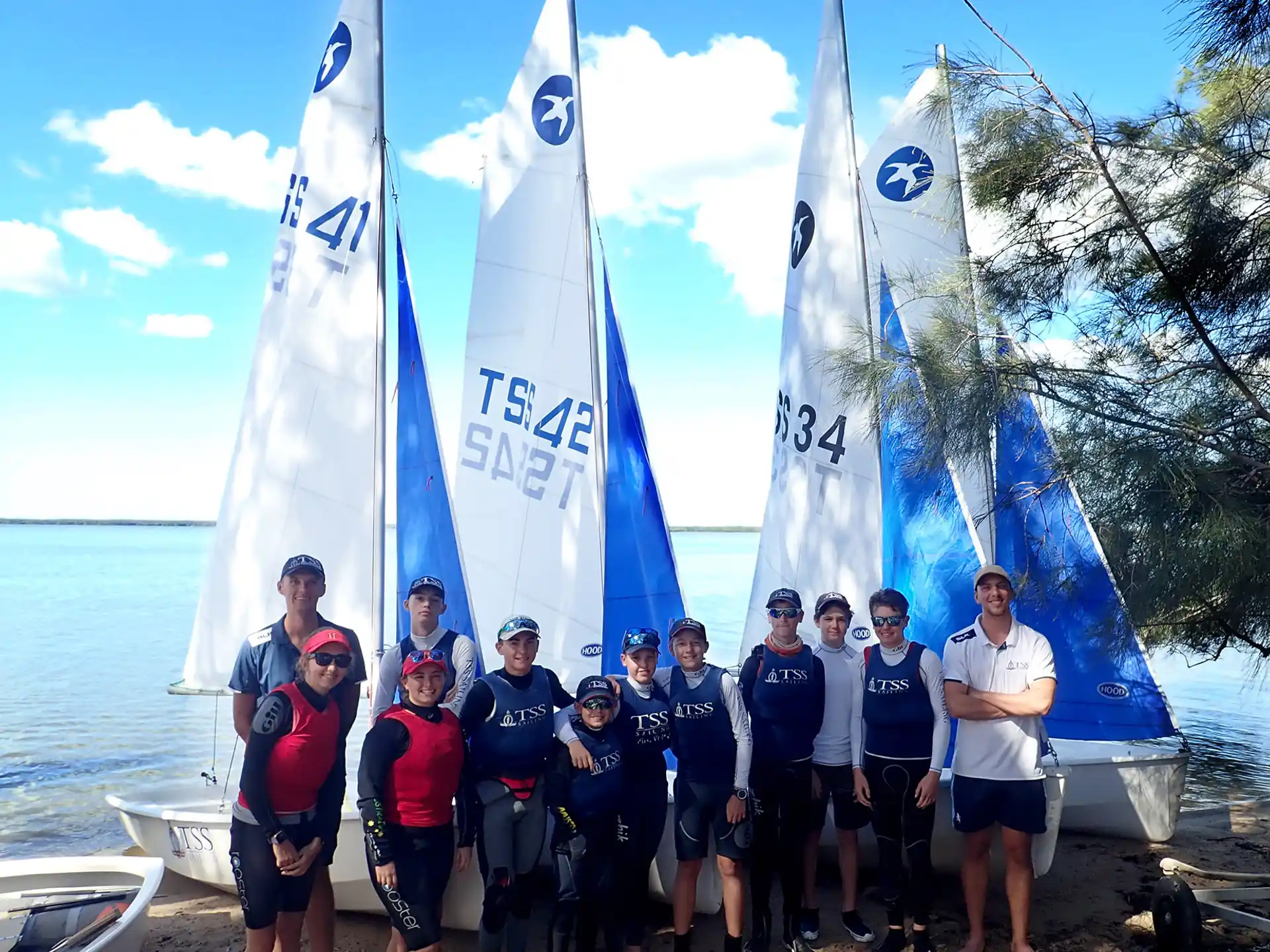 a group of people standing next to a row of sailboats