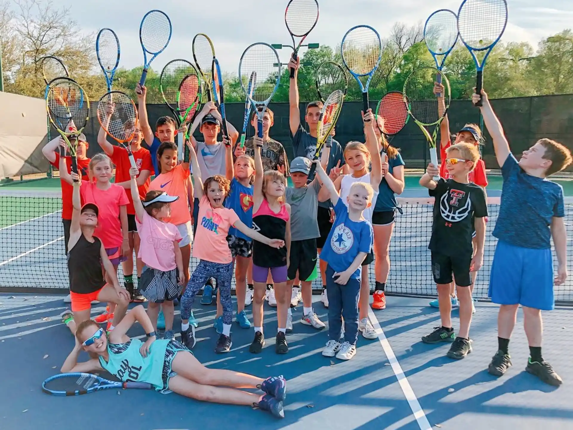 a group of kids holding tennis rackets and posing for a photo