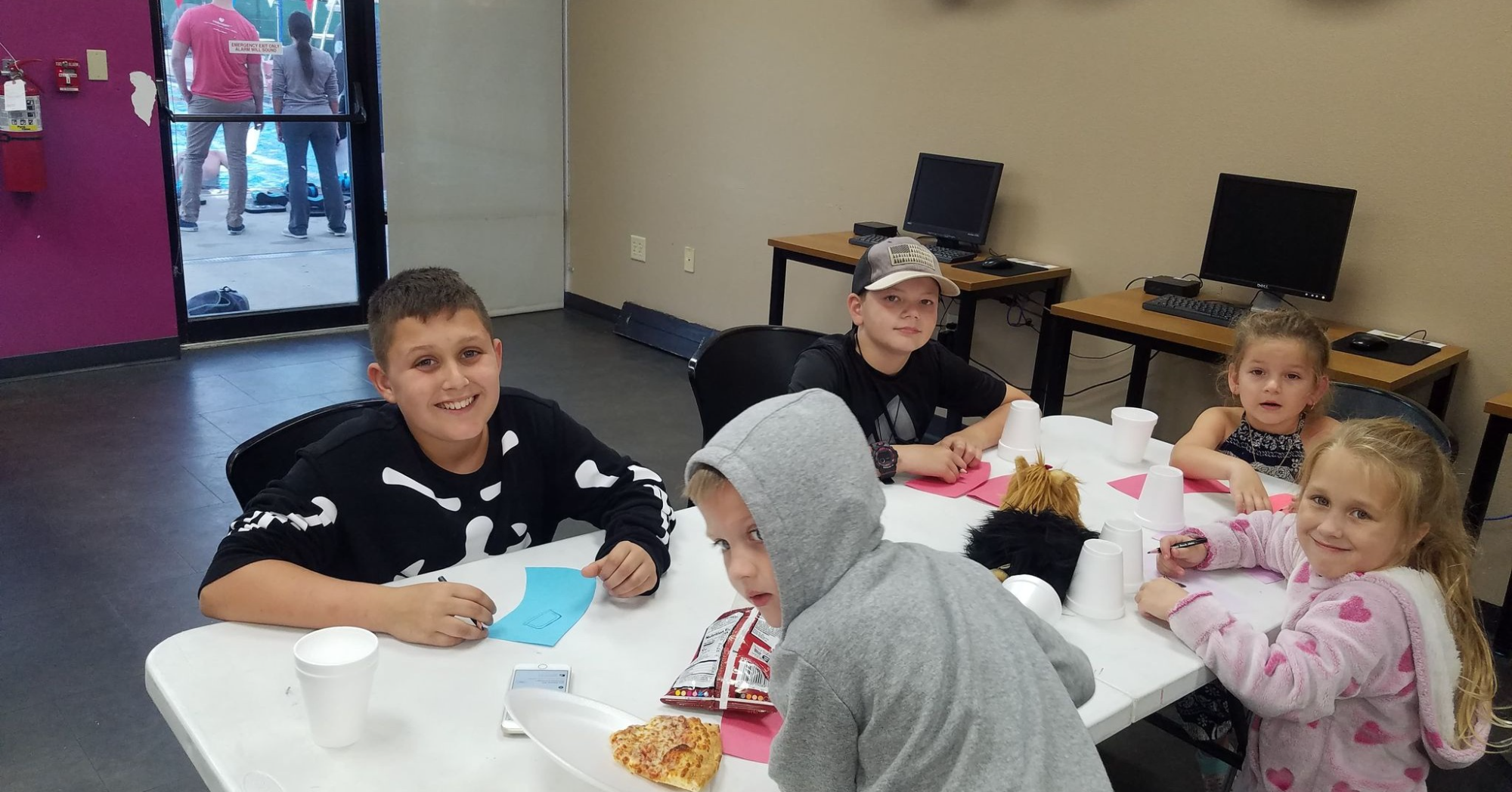 a group of people sitting at a table with food and drinks