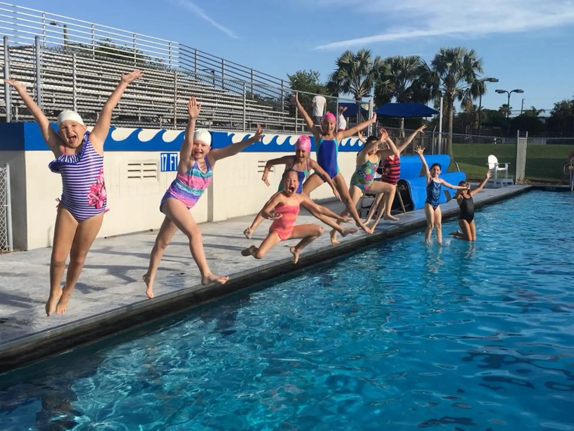 a group of people jumping into a pool