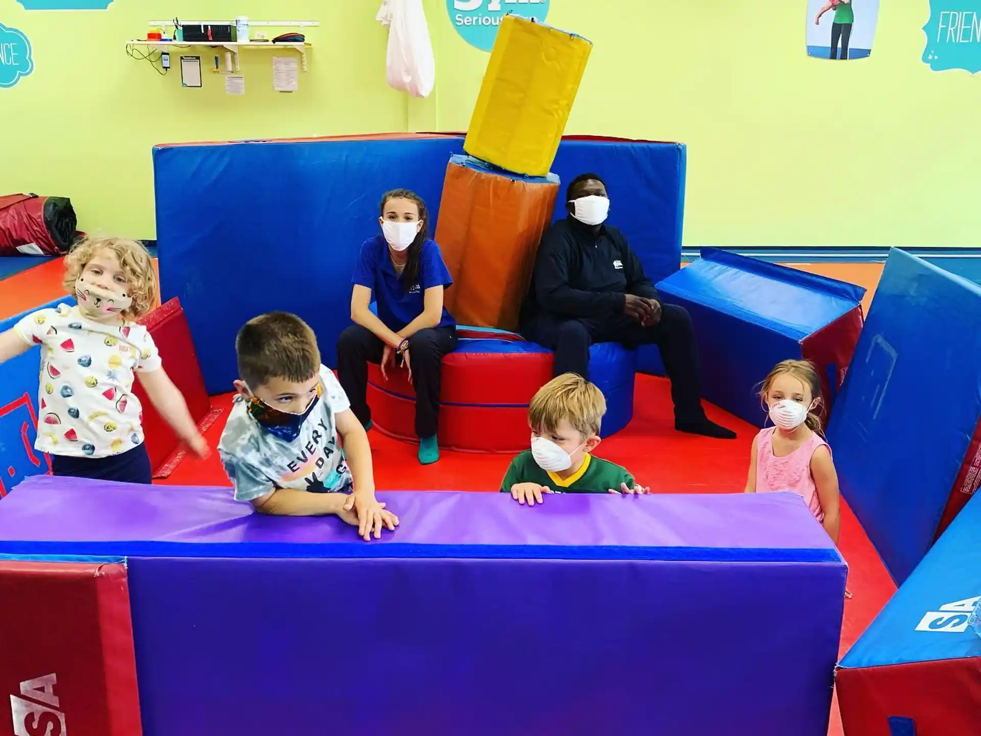 a group of children sitting on a colorful play set