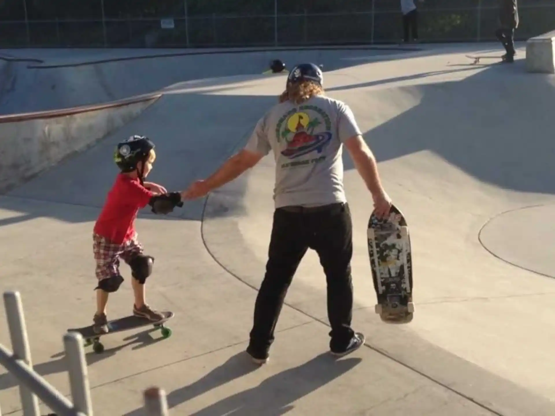 a man and a boy riding skateboards at a skatepark