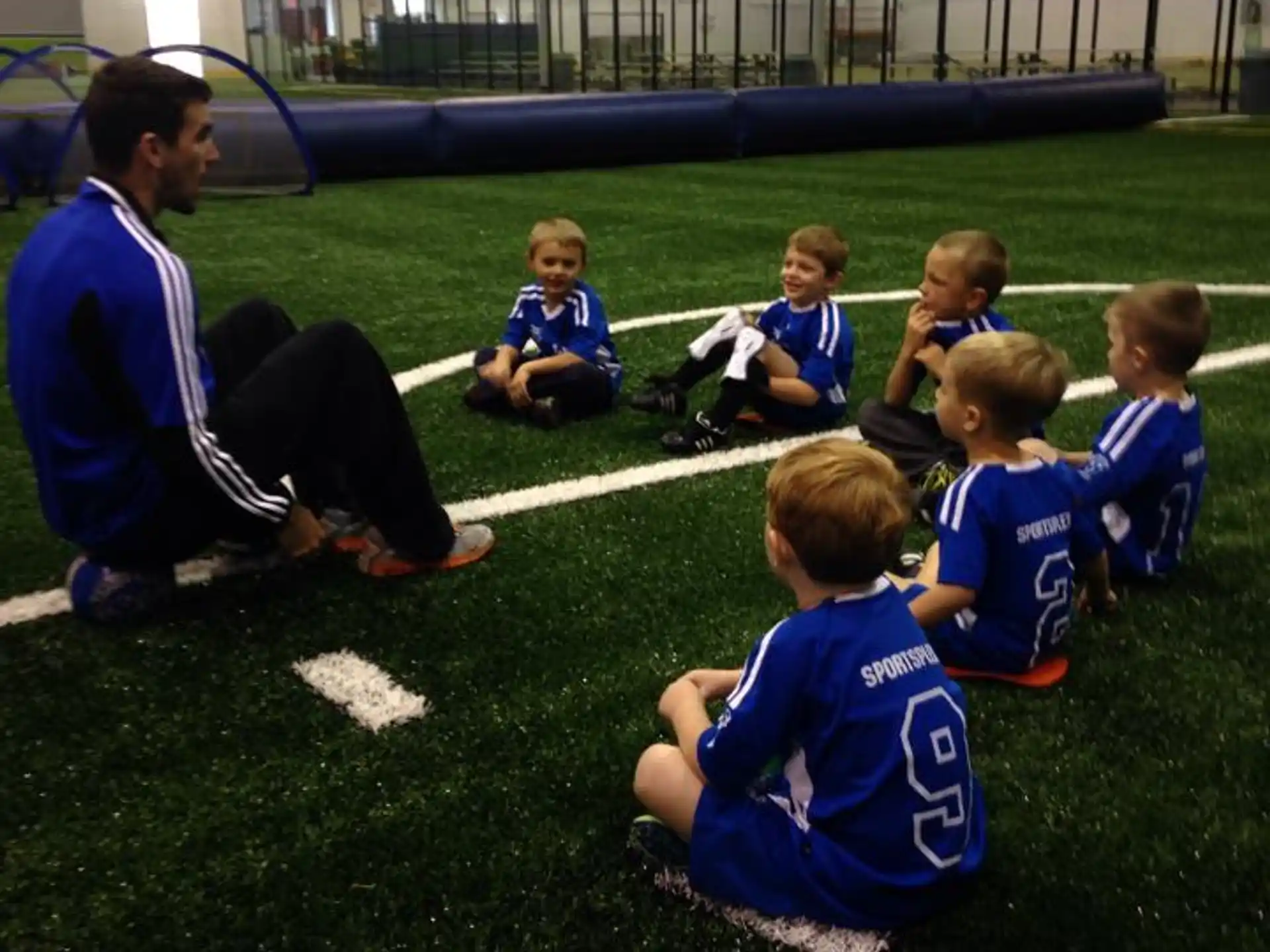 a person kneeling with a group of kids on the grass