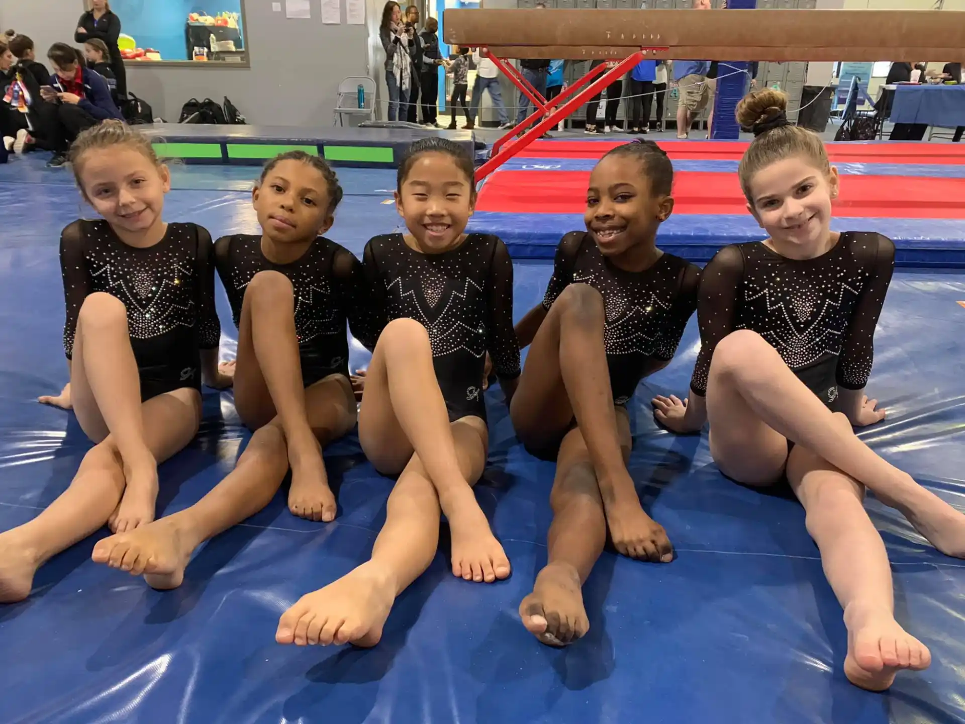 a group of girls in swimsuits sitting on a mat