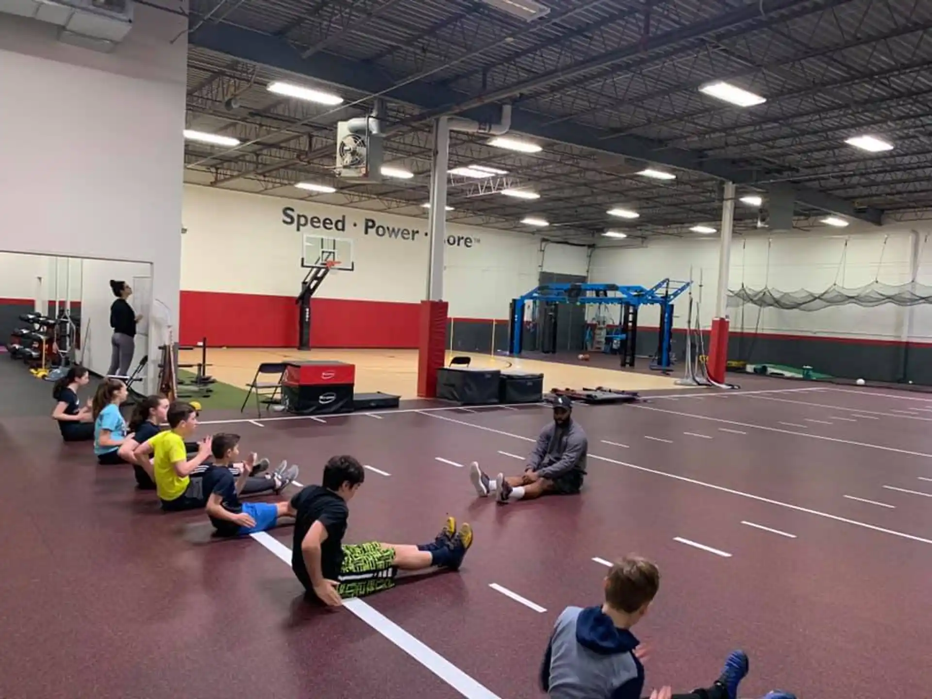 a group of people sitting on the floor in a gym