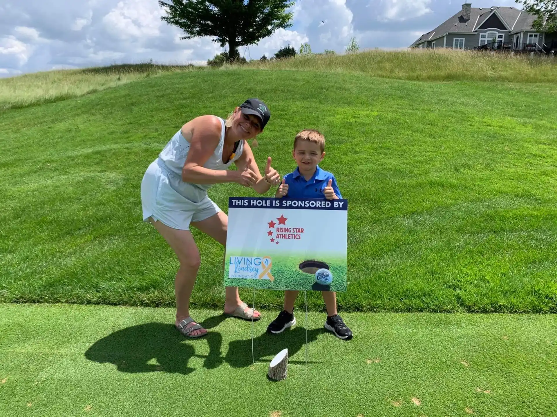 a person and a boy holding a sign in a grassy field