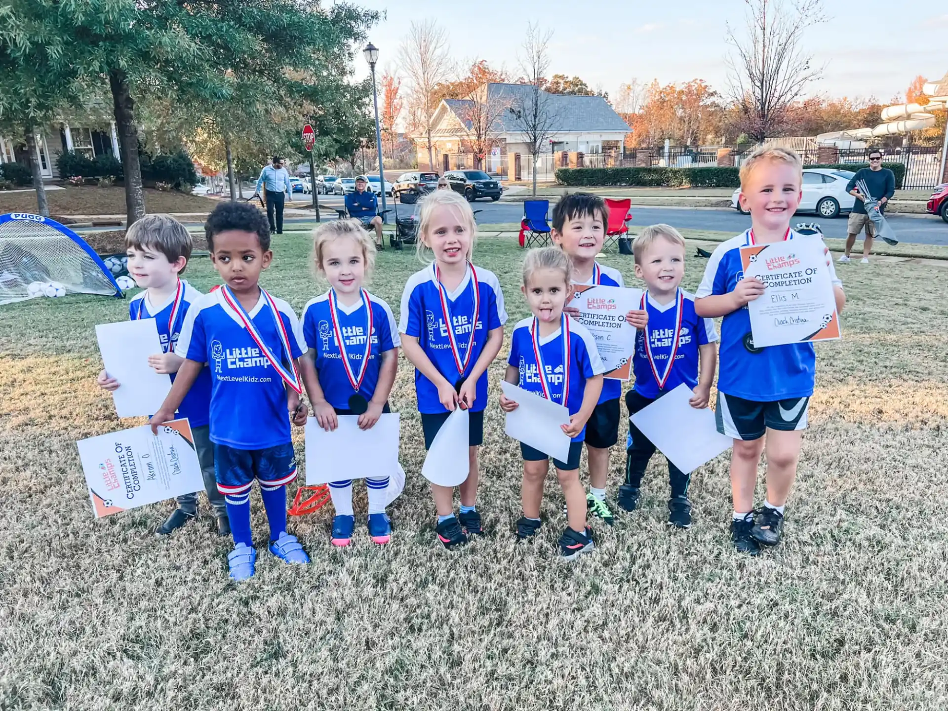a group of children in matching blue shirts standing on grass