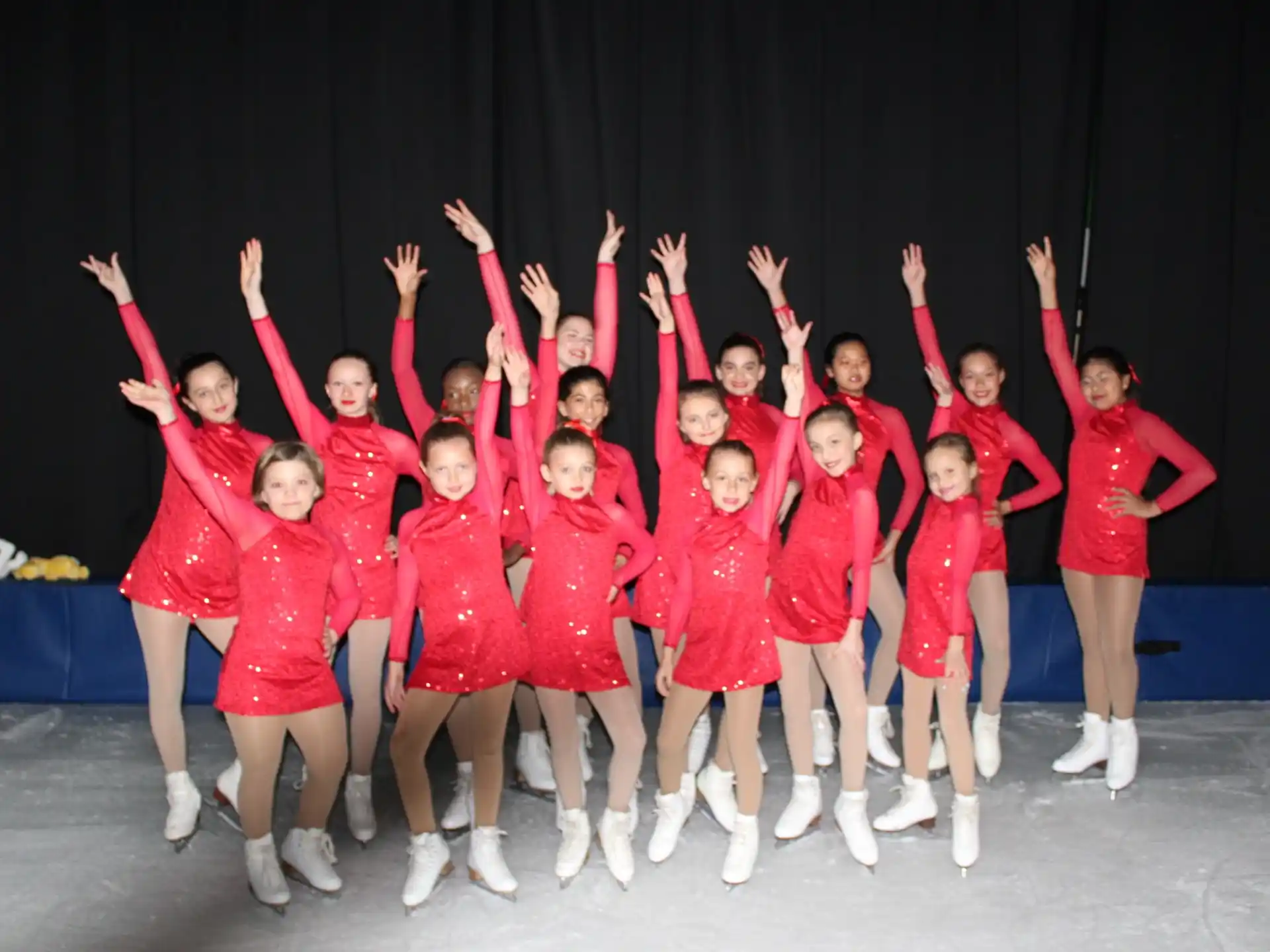 a group of girls in red and white uniforms holding their arms up