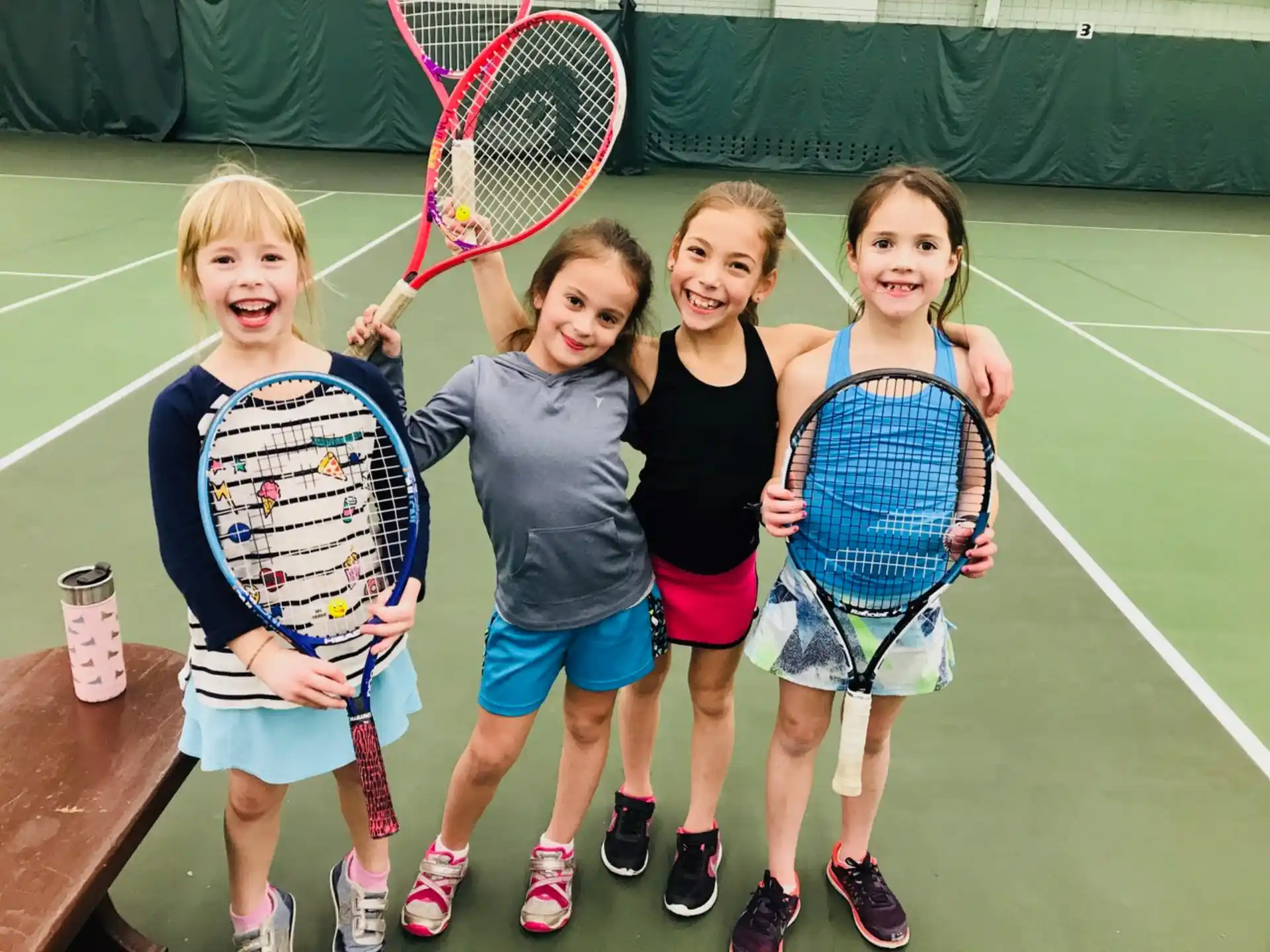 a group of girls holding tennis rackets