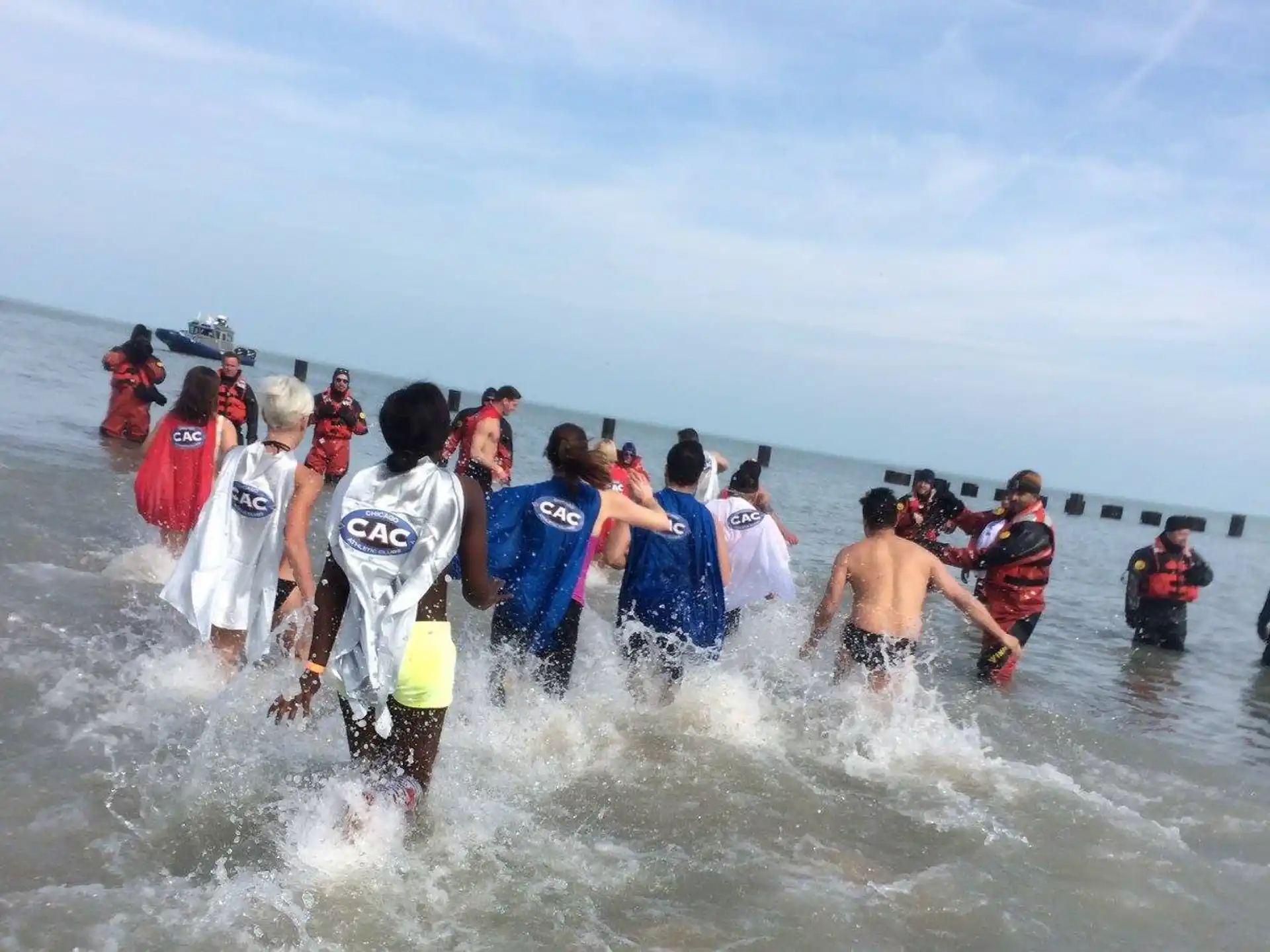a group of people in wet suits running through water