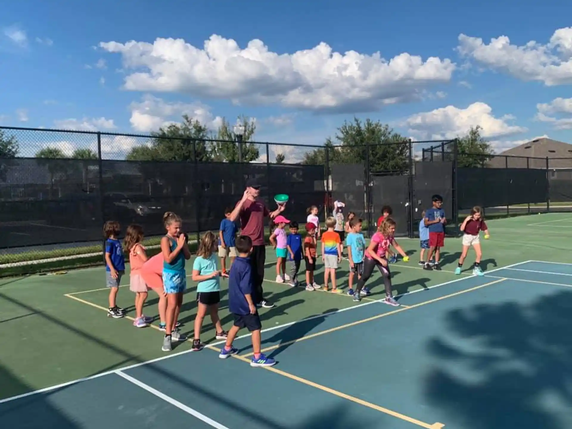 a group of kids standing on a tennis court