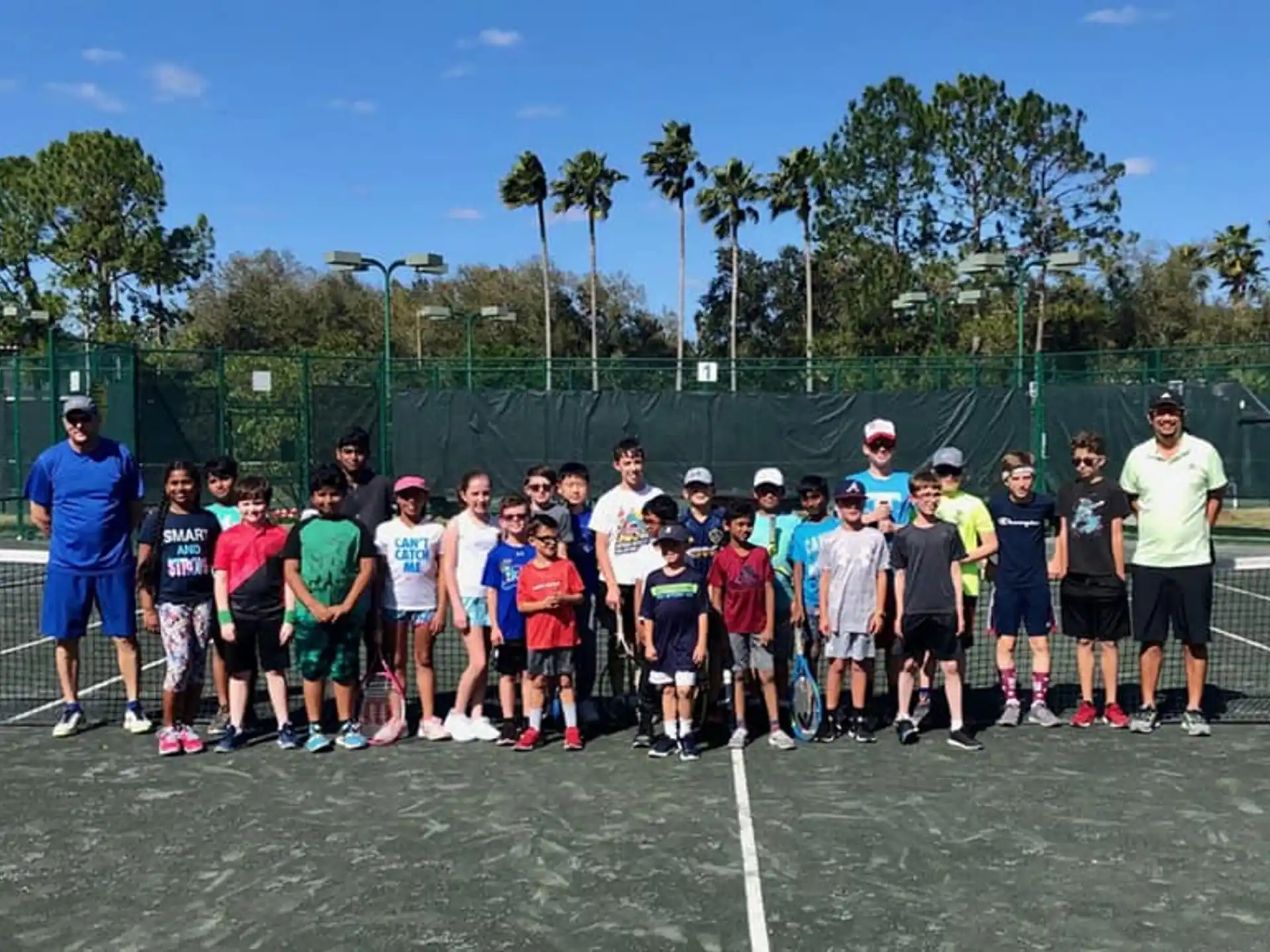 a group of people posing for a photo on a tennis court